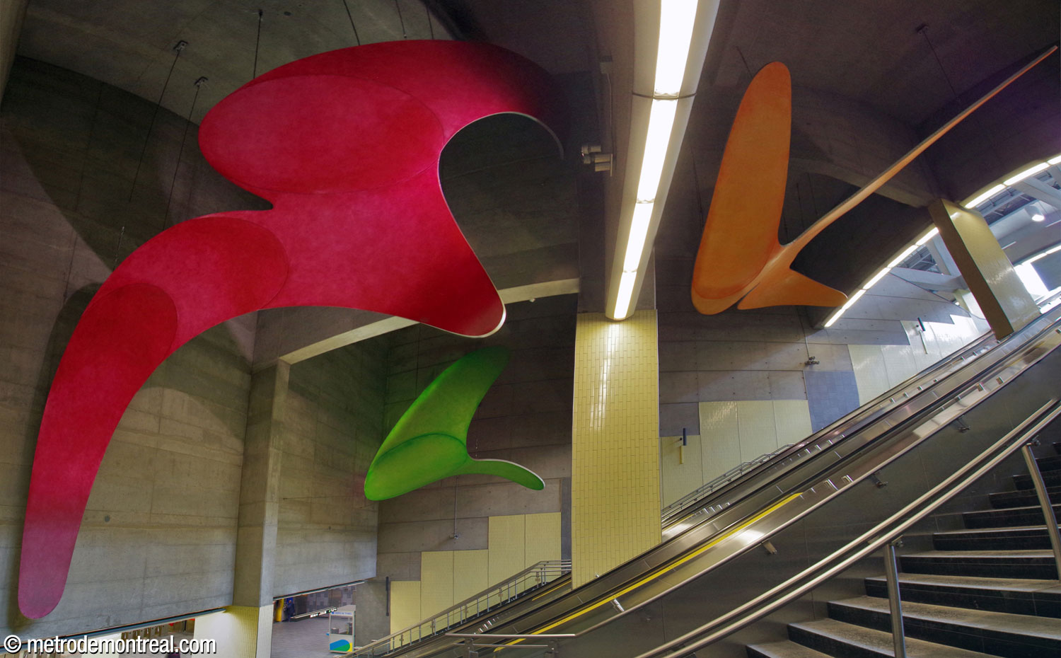Overview of Hélène Rochette's sculptural cycle Les fluides, with three brightly coloured, flamboyantly curved elements suspended in the huge volume above the main stairwell down to the ticket hall.