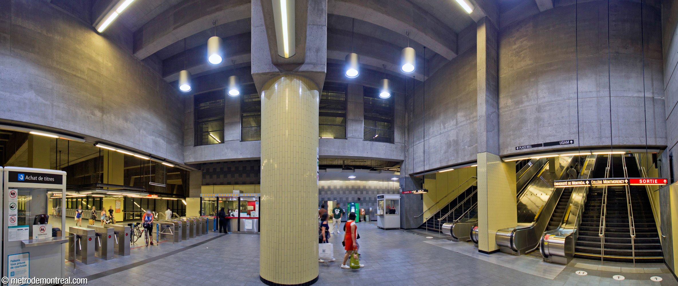 Panorama of the ticket hall. At left, the lengthy gateline leads directly to the platform stairs and crossover, as at all the Laval stations. At right, a sprawling stair and escalator well leads upward. In the background, a recessed area contains ticket machines and gives access to the elevator to the surface and a direct access to the parking garage.