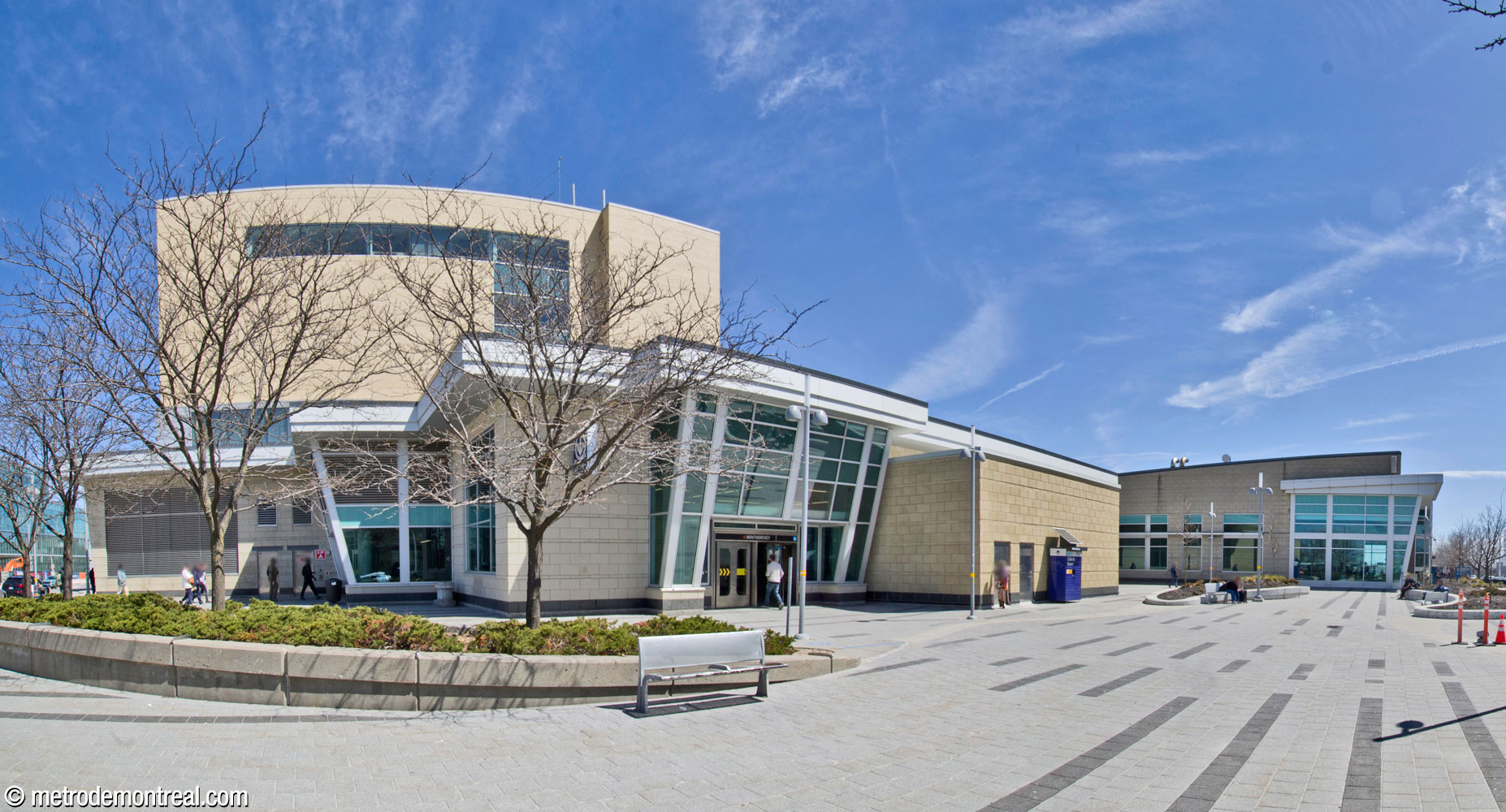 The metro station's independent headhouse (left), clad in pale yellow blocks, is located north of the bus terminal building (right).