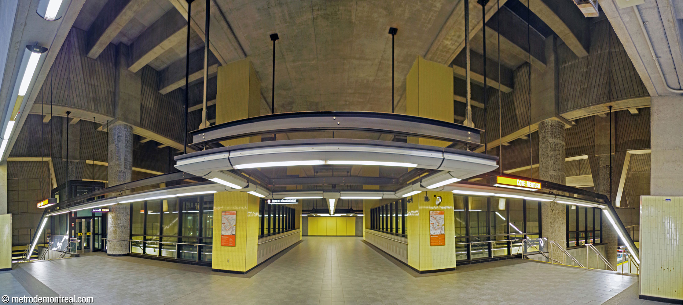 The transept intersects with the trainroom at the same level as the ticket hall; the glass-enclosed crossover is framed by pillars clad in yellow ceramic. The departure (Côte-Vertu) platform is accessed by the two staircases closer to the ticket hall.