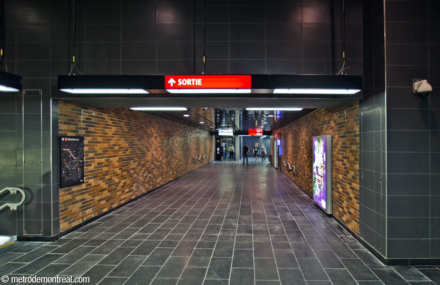 The enclosed crossover that connects the new stairwell between the headhouse and the Côte-Vertu platform with its counterpart on the Montmorency side. It repeats the station's original terra cotta brickwork.
