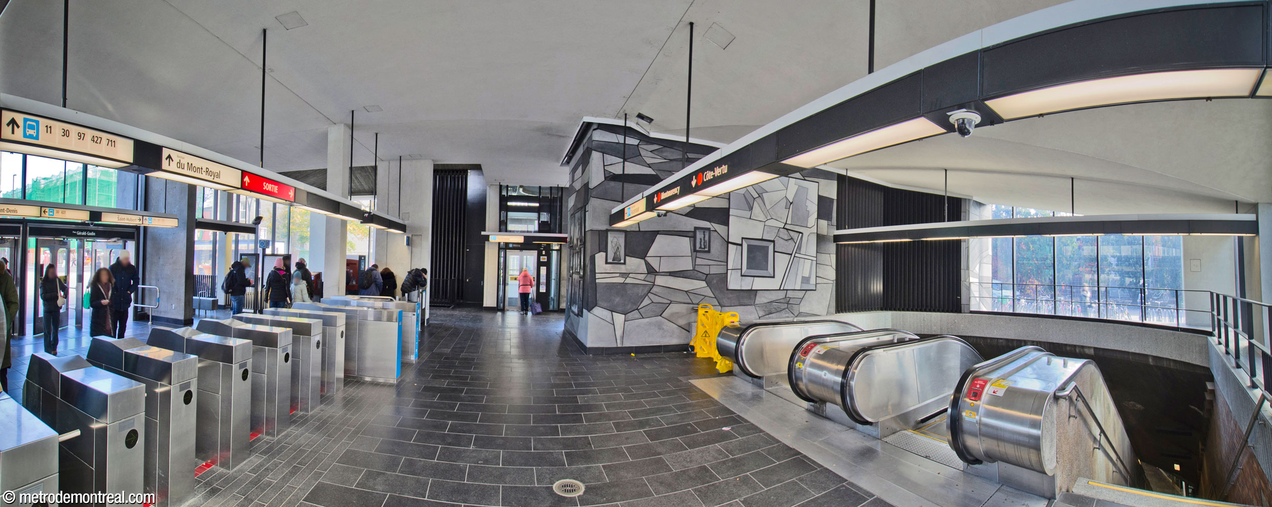 The interior of the headhouse, looking eastward from within the fare-paid zone near the ticket booth. The main gateline is at left; at centre in the background is the elevator to the platforms. The original stairs and escalators are at right, with Simon Bilodeau's mural Je reviens chez nous above them.
