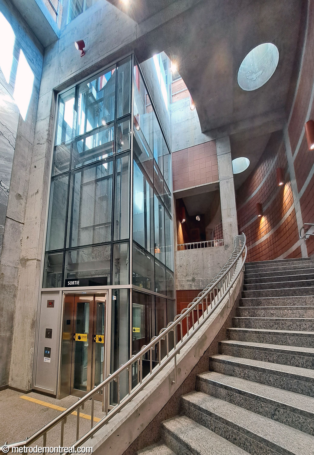 Another view of the stairwell and elevator shaft between the surface and the ticket hall level. Note the opening around the elevator shaft that admits daylight, as do the round skylights that illuminate the stairs.