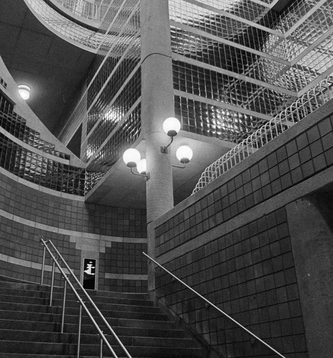 The concrete pillar at the centre of the light shaft previously had four globe lights marking the stairs to the Snowdon platform, mirroring the four globe lights on the lamppost on the Saint-Michel platform. Today, only one lamp remains.