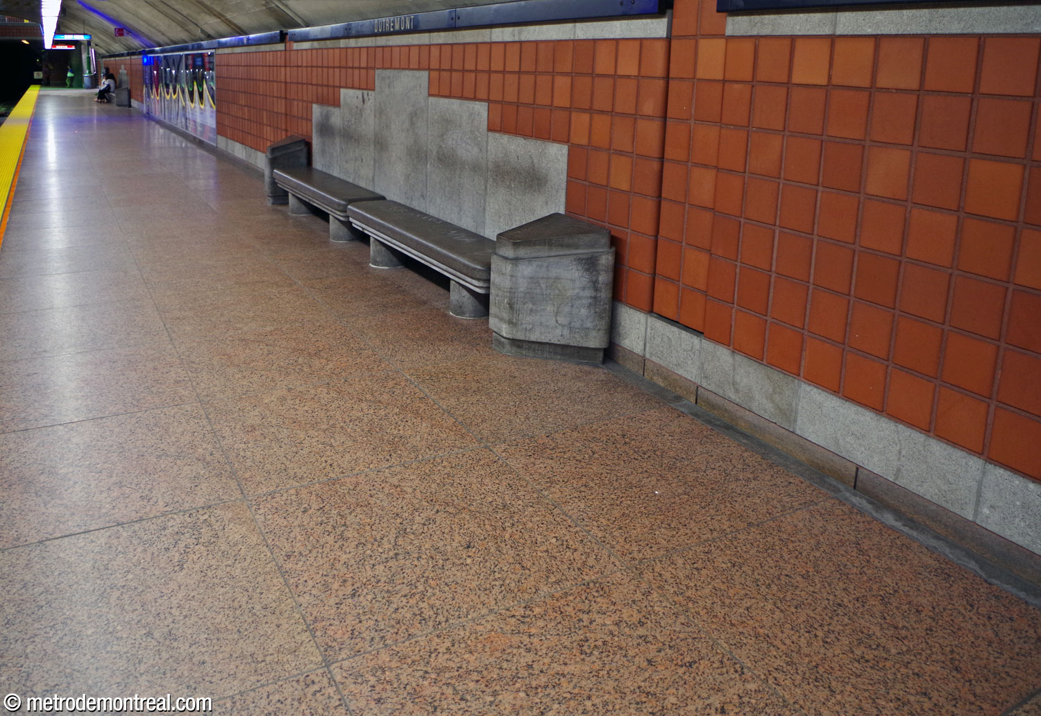The materials used on the platforms: terra cotta wall tiles, rough light grey limestone trim and panels behind the dark grey stone benches, and pink-brown granite floors.