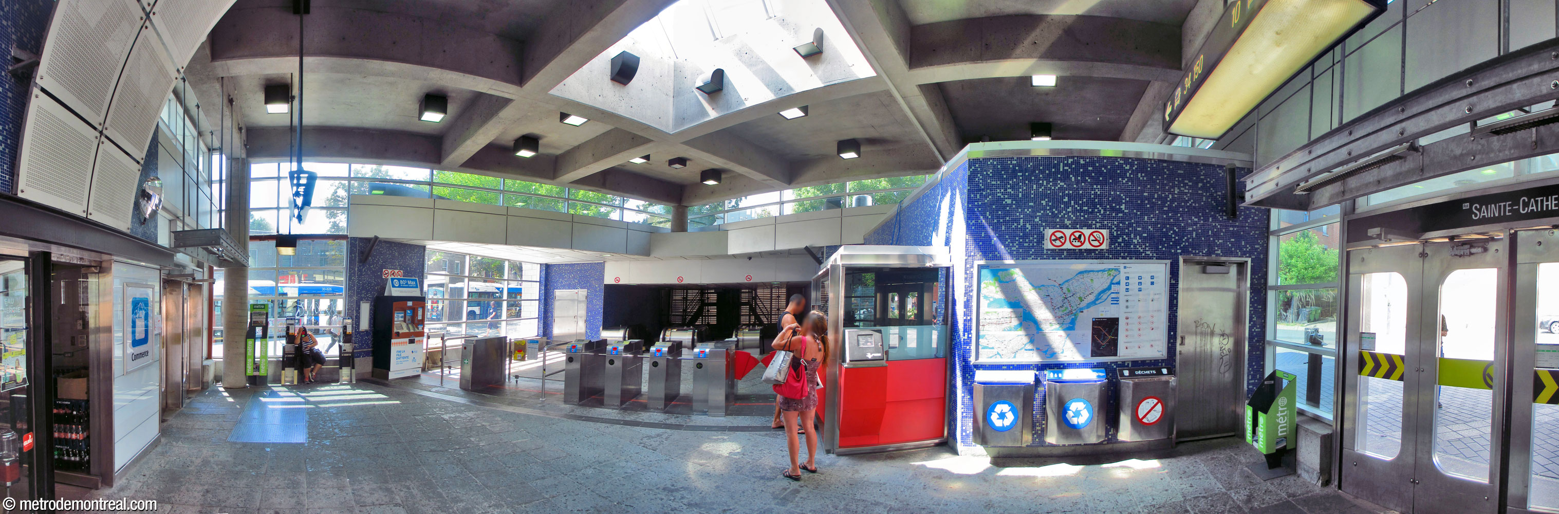 Interior of the headhouse, with the western exit at left and the eastern one at right. Surfaces are clad in blue mosaic. A clerestory illuminates the whole perimeter of the building, along with a skylight in the centre of the ceiling.