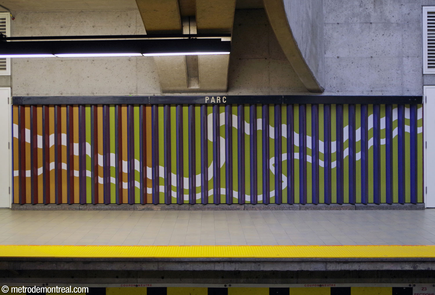 La même portion de la frise murale de Huguette Desjardins démontre l'effet tabula scalata. En regardant de devant, on voit une surface jaune-orange et vert citron avec des bandes blanches tourbillonnantes.