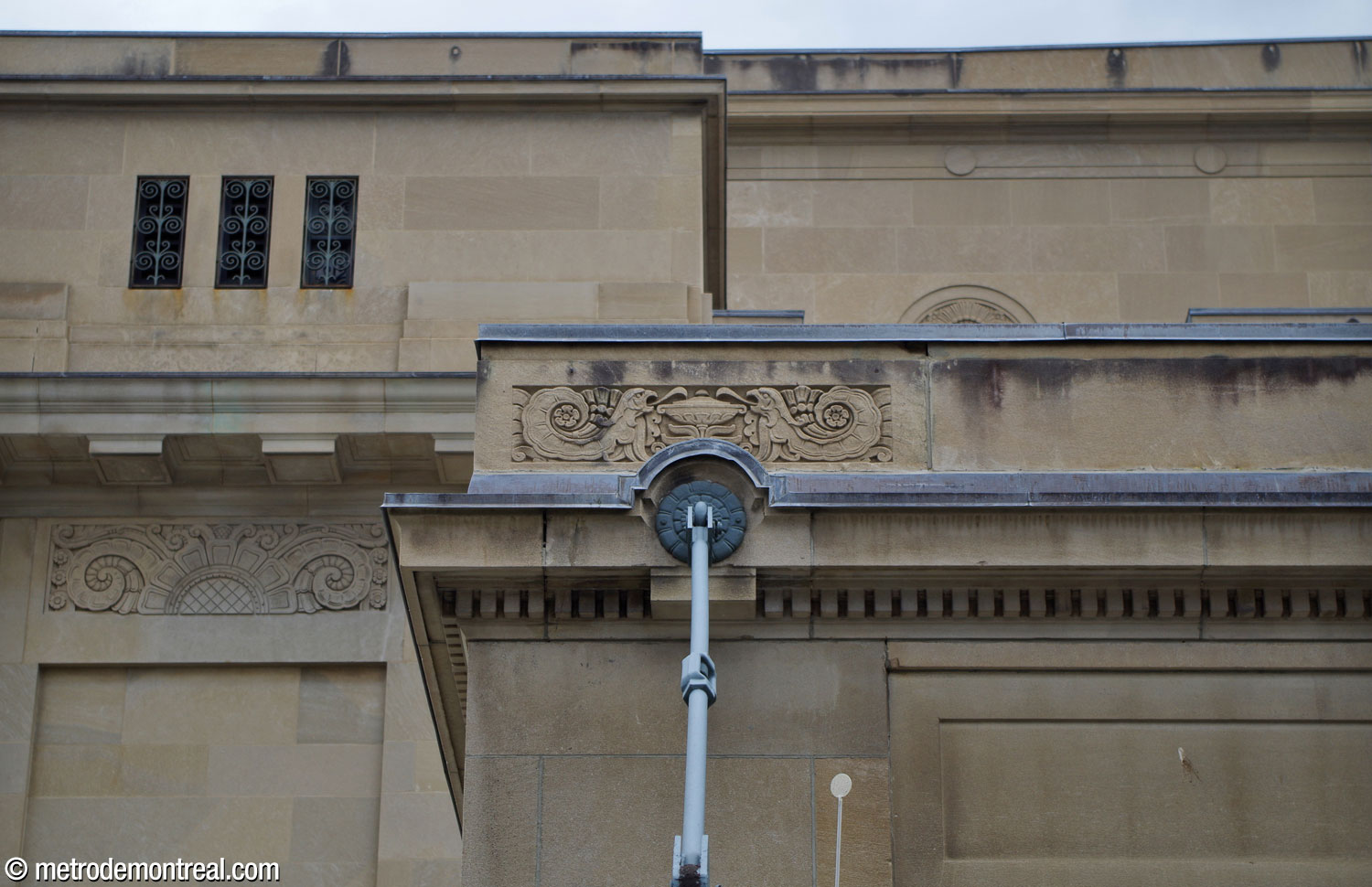 Détail des reliefs décoratifs sur la façade ouest de la gare Jean-Talon, au-dessus de l'entrée du métro. Ici, des figures d'animaux imaginaires entourent l'un des ancrages de la marquise au-dessus de l'entrée.