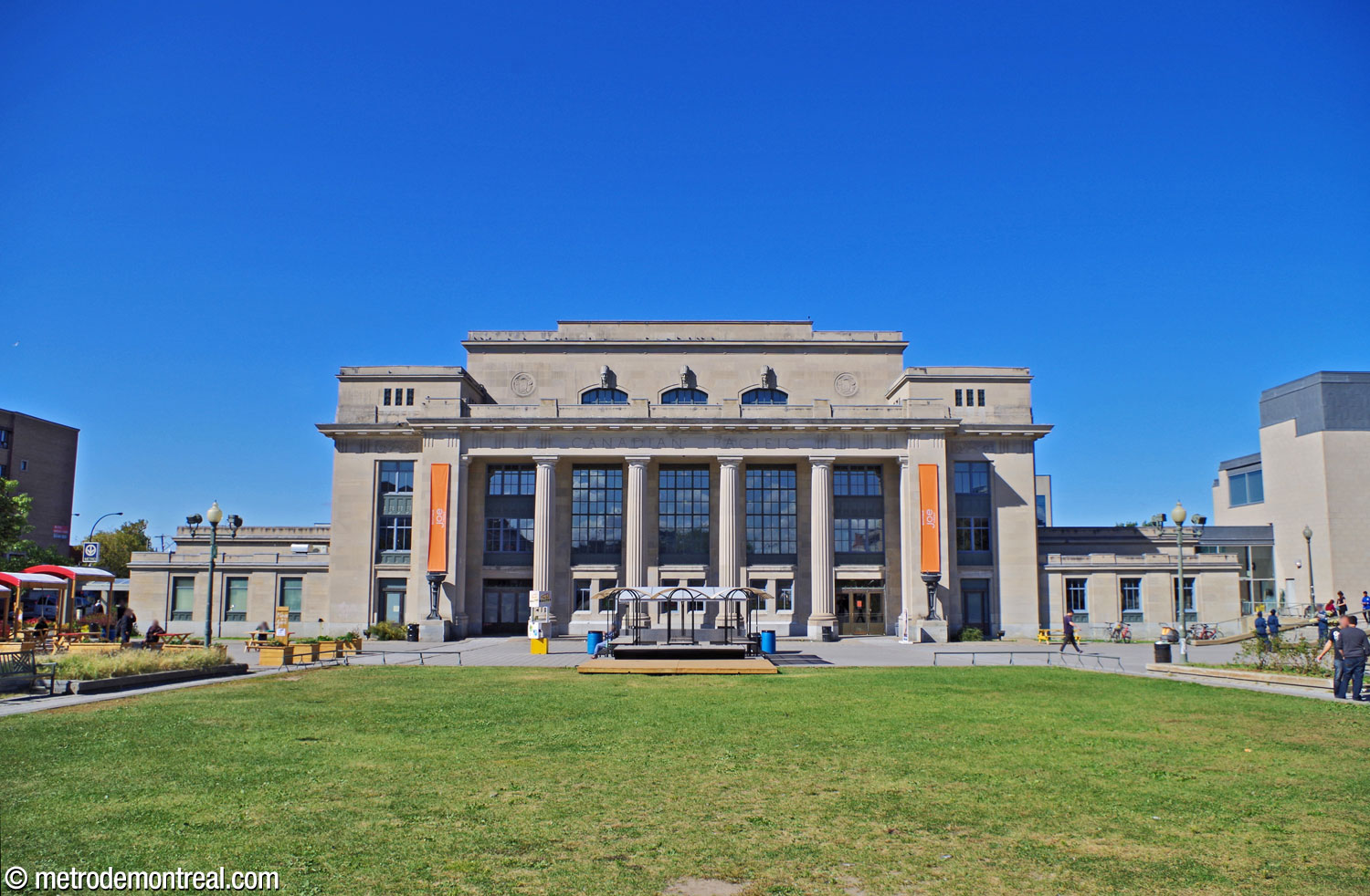La façade principale de la gare patrimoniale Jean-Talon, vue du sud (place de la Gare-Jean-Talon). Les éléments néoclassiques tels que sa symétrie et sa colonnade l'inscrivent dans le style architectural Beaux-Arts, en complément du style Art déco de son intérieur. L'accès à la station de métro occupe l'aile du côté gauche du bâtiment; les portes, sur le côté et l'arrière de cette aile, ne sont pas visibles ici.