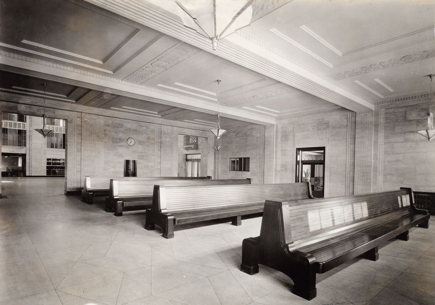 La salle d'attente de la gare Jean-Talon (aujourd'hui l'accès au métro) en 1931. Les ouvertures dans le mur du fond, aujourd'hui fermées, mènent à la salle des pas perdus. À noter, les lampes plafonnières et la fontaine à boire sur le mur du fond, toutes encore in situ.