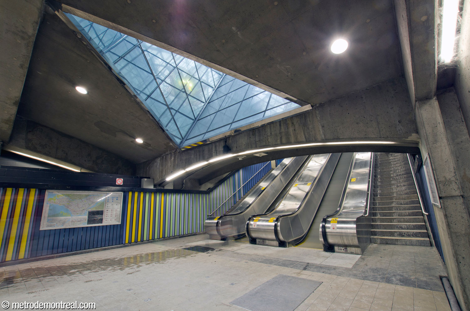 Le pied des escaliers vers la sortie. En haut, la bouche du puits de lumière de forme triangulaire, dont l'intérieur est revêtu de miroirs.