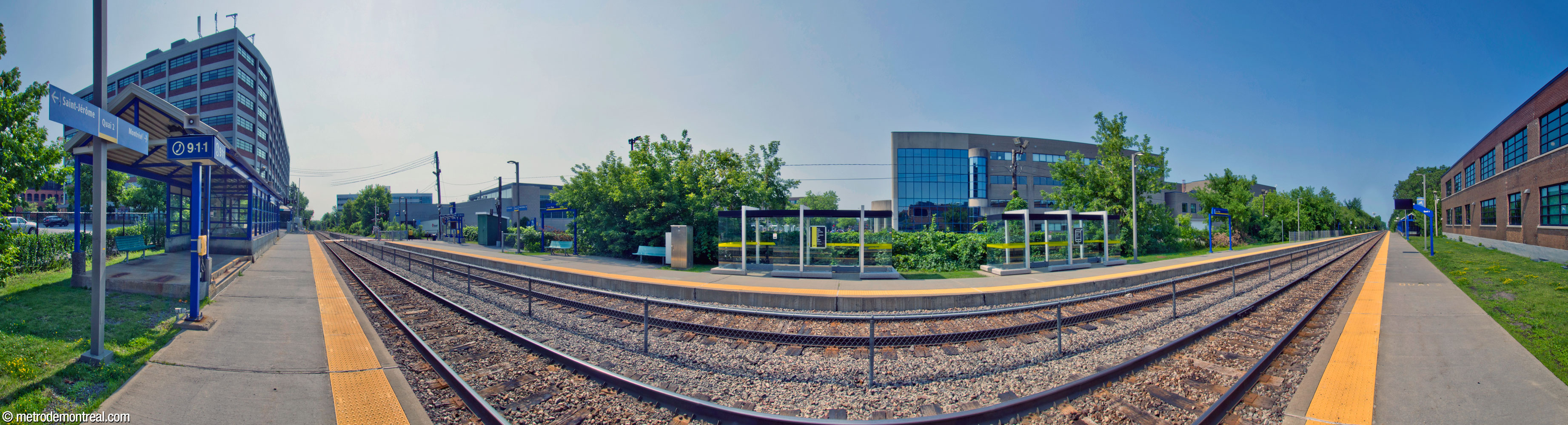Panorama de la gare Parc, vue à partir du quai en direction de la banlieue, plus loin vers le nord. Le quai en direction du centre est doté d’abris en verre, plus récents mais plus petits.