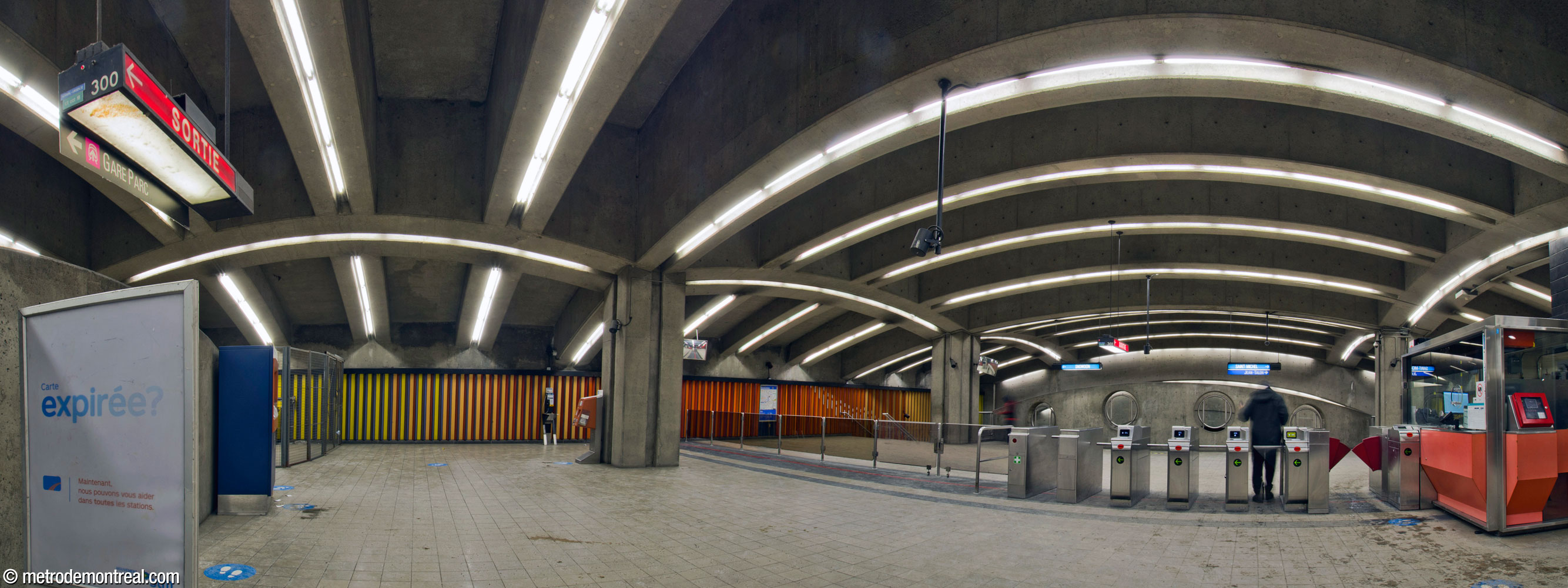 Panorama de la billetterie. Les escaliers vers la sortie se trouvent derrière le photographe. À droite, la ligne de perception avec sa loge donne accès aux escaliers vers les quais et au parapet à l'extrémité est de la mezzanine.