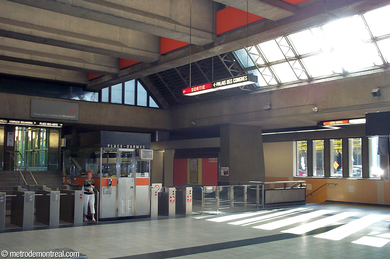 L'ancien aménagement plus typique des barrières de perception de la station, qui traversaient alors le hall pour créer une zone contrôlée centrale. Cette photo présente également l'escalier ouest vers le quai Côte-Vertu avant qu'il ne cède sa place, tout comme son pendant du côté Montmorency, à un ascenseur.