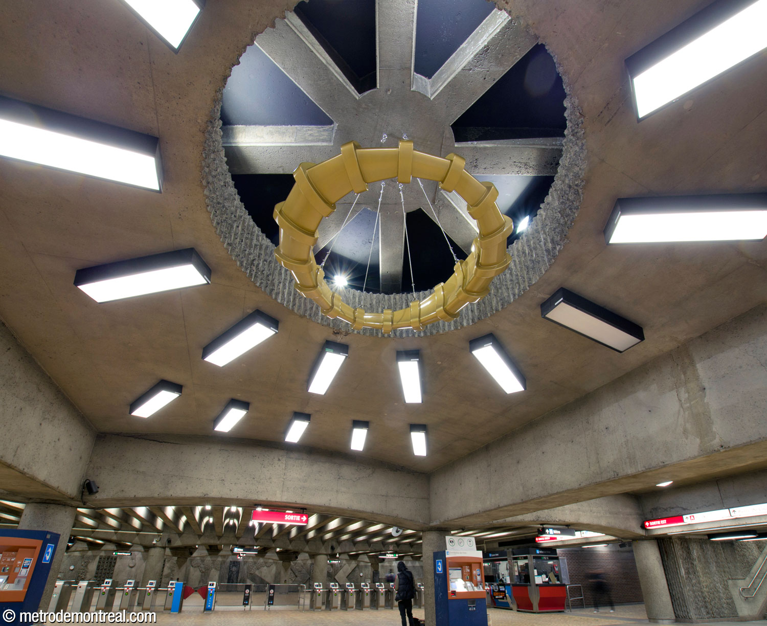 The middle of the three suspended sculptures in the concourse, part of the work Point de mire by Francis Montillaud, this one coloured gold, seen in context.