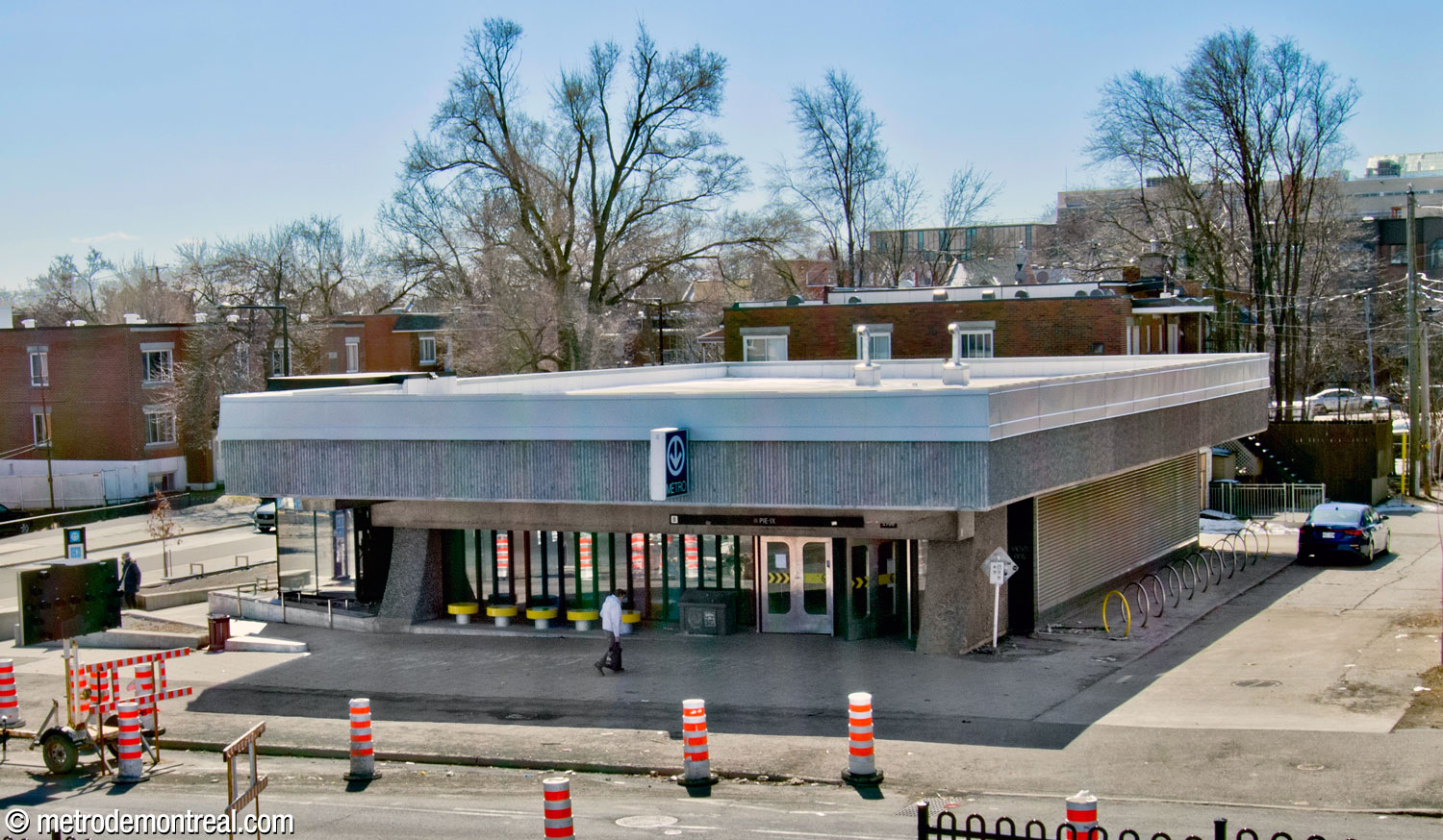 The Pie-IX Ouest headhouse, seen from the Olympic Stadium esplanade. Note the wide overhang of the roof in roughened ridged concrete and the curved, high-aggregate abutments framing the front glass wall.