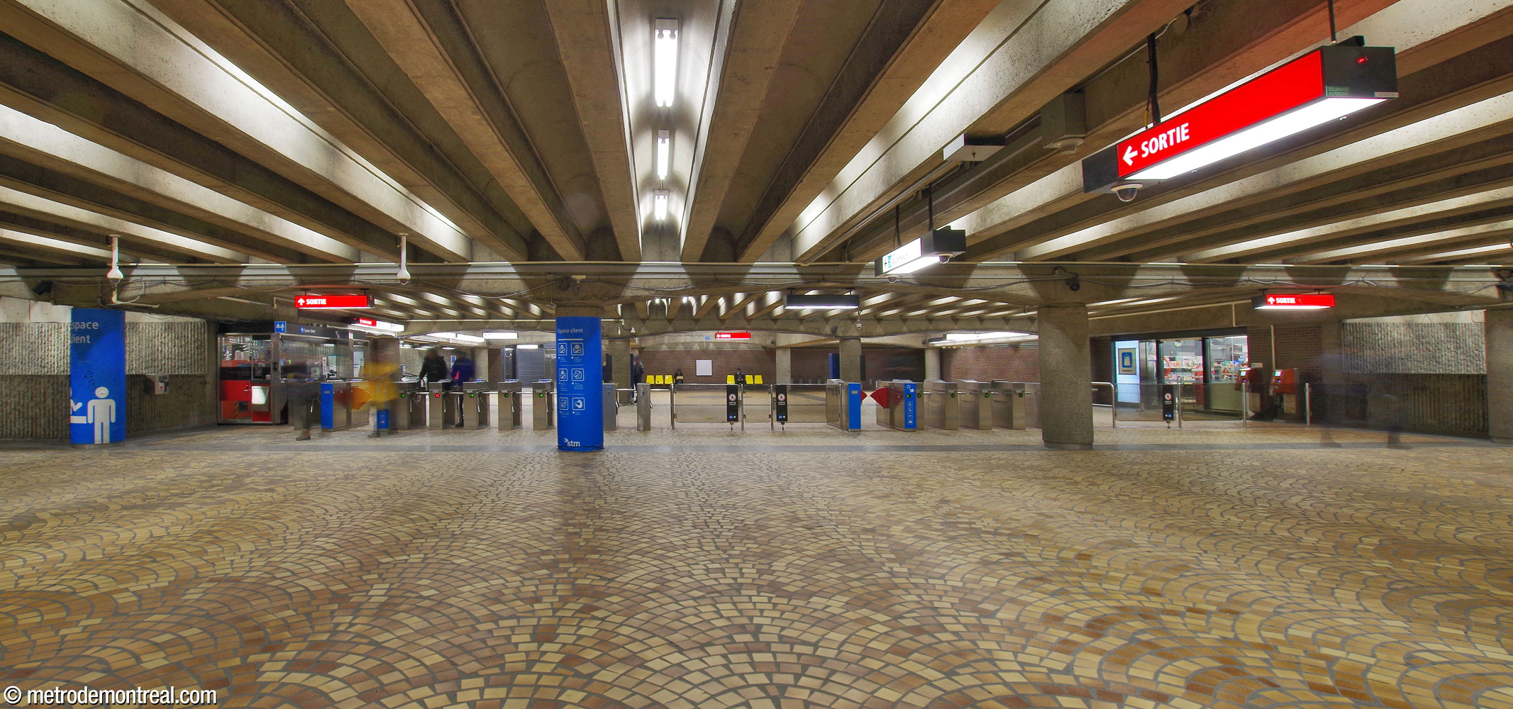 A view out from the mezzanine toward the long ticket barrier and the concourse.