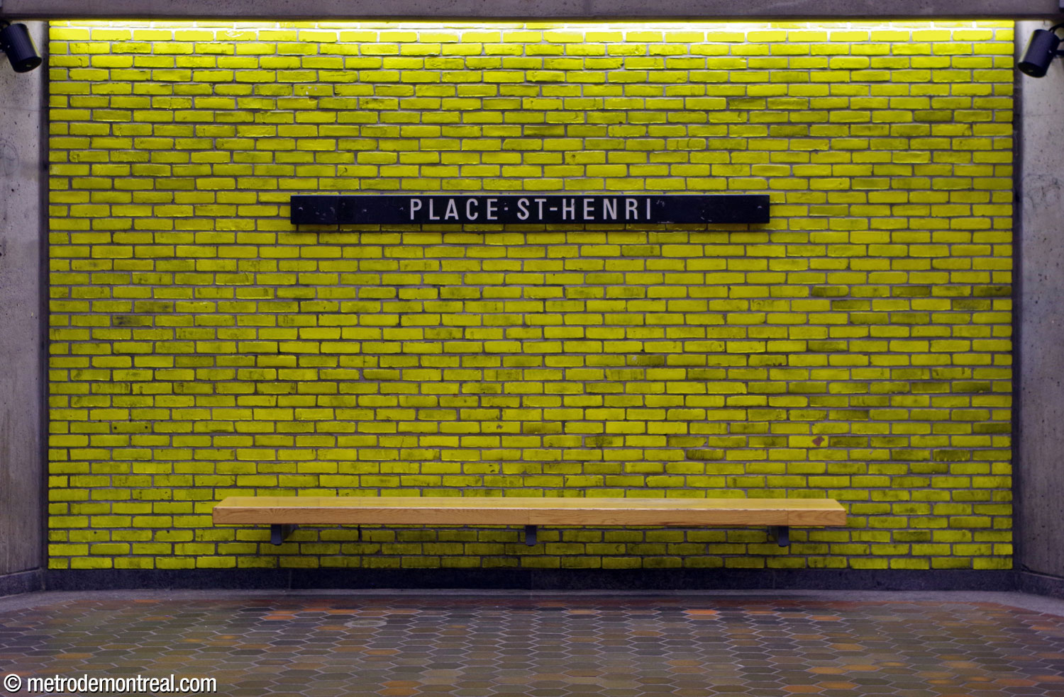 One of the station's wooden benches, within one of the panels of coloured glazed tiles framed by pillars in the central part of the trainroom.