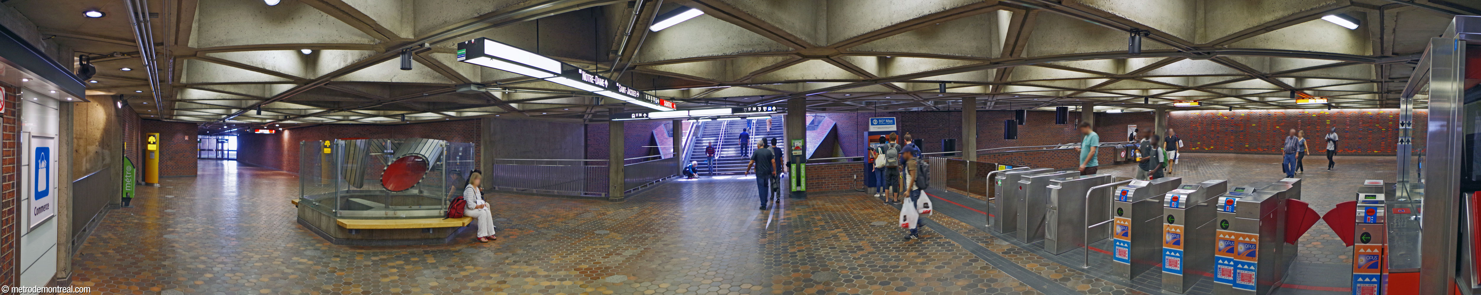 Panorama of the station's concourse, collecting foot traffic from the station’s various entrances. A bridge (centre) leads to the foot of the stairs to the Saint-Ferdinand headhouse, flanked by the light shafts to the Montmorency platform. The gateline leads to the fare-paid zone (right) that in turn leads to the escalators to the platforms. The upper portion of Jacques de Tonnancour's mobile is at centre-left, and the mural Bonheur d'Occasion by Julien Hébert is at right, on the back wall of the fare-paid zone. The triangular-coffered ceiling is overhead. This panorama was taken before the open-air entrances (left) were replaced and the hallway extended to connect with the new headhouses.