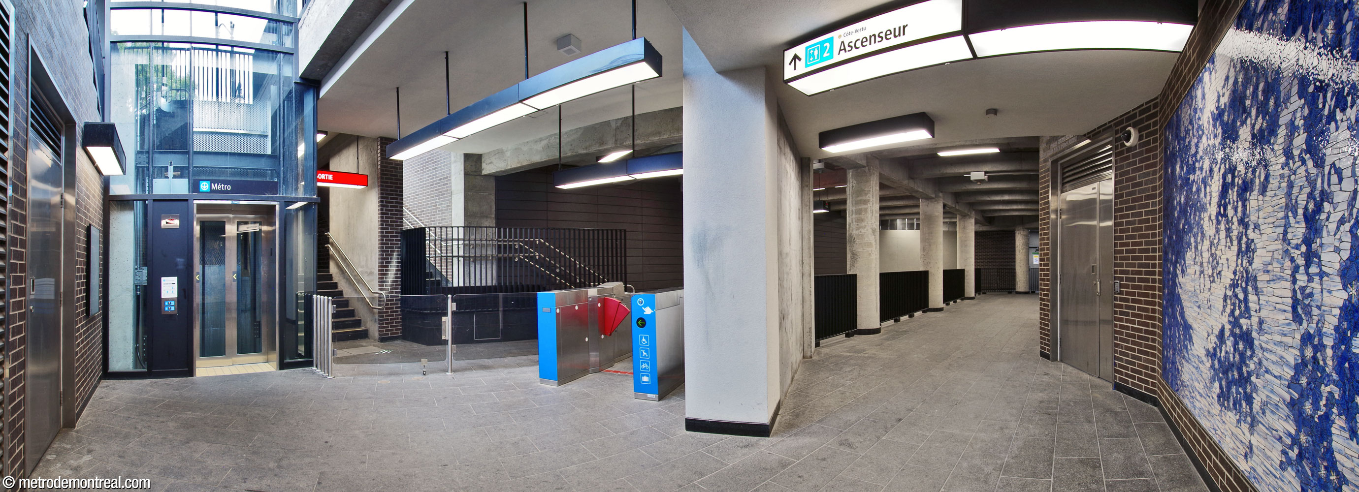 Panorama of the fare-paid zone below the Place Saint-Henri headhouse. The elevator between the surface and the Montmorency platform is at left; at right, the fare-paid zone continues to the other elevator. At centre-left, the two separate staircases down from the headhouse lead to the fare-free zone of the corridor. Véronique La Perrière M’s mural Rives scintillantes is at right.