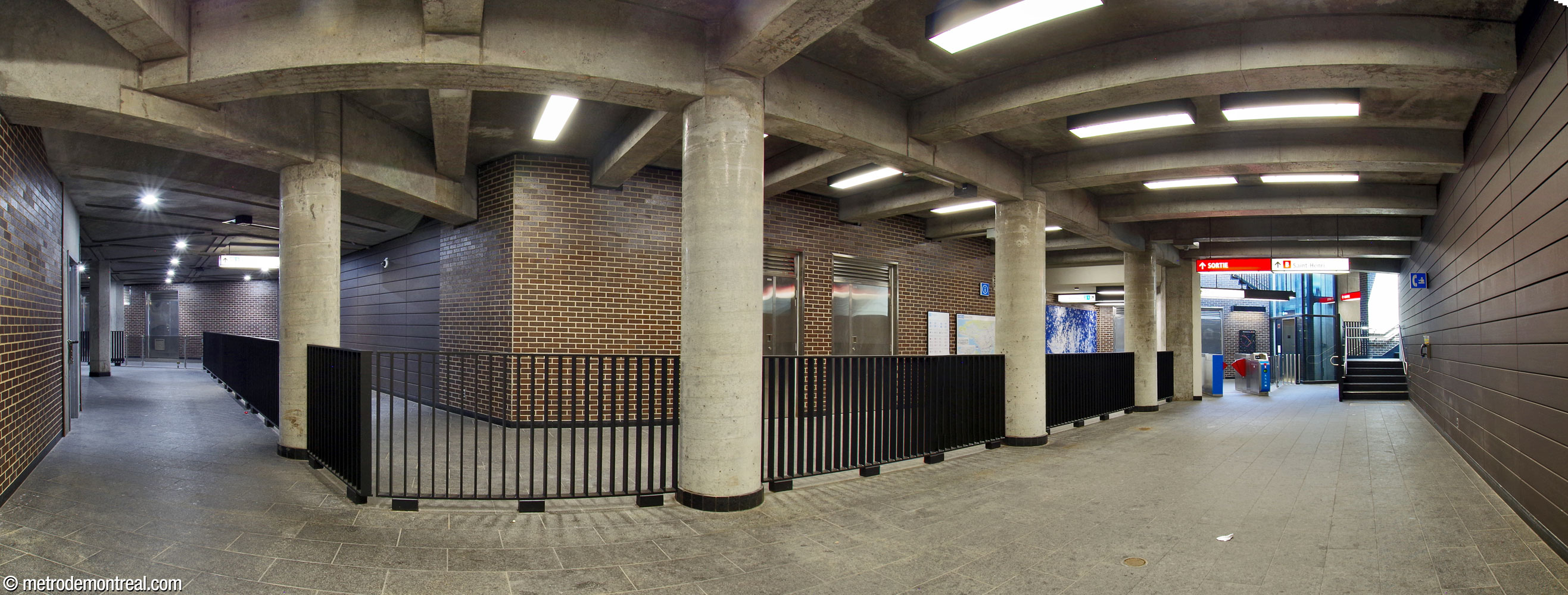 The hallway leading to the Place Saint-Henri headhouse. The fare-free half of the hallway is in the foreground. The fare-paid zone (background) runs along the hallway to reach the elevator between the surface and the Montmorency headhouse, right. A fare gate provides access to that elevator. The two flights of stairs at far right lead up to the headhouse. The main section of Véronique La Perrière M’s artwork Rives scintillantes is at centre-right. At the top far left, note how the concrete ceiling beams in most of the hall give way to flat triangular coffers; the latter section was part of the outdoor underground gallery between the former open-air exits.