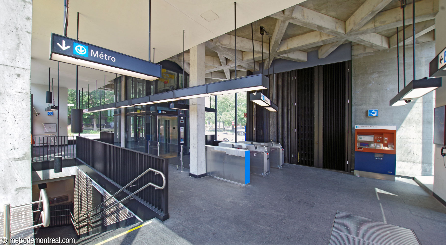 The interior of the Place Saint-Henri headhouse from the southwest corner. At left, one of the headhouse’s two stairwells leads down into the station. At centre, two fare gates lead to the elevator down to the ticket hall level and Montmorency platform.