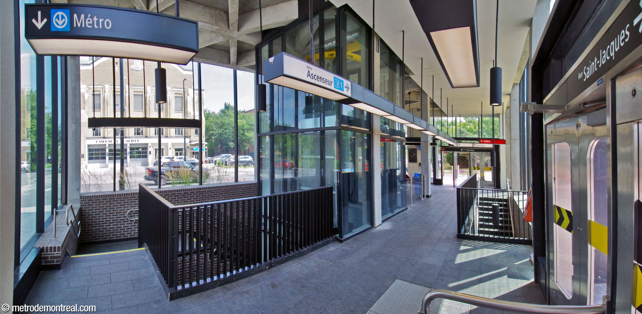 The interior of the Place Saint-Henri headhouse from the northwest corner. The headhouse contains two separate narrow stairwells down into the station at opposite corners, left and right. The elevator shaft is at centre. At centre-right, a walkway leads to the fare gates for the elevator.