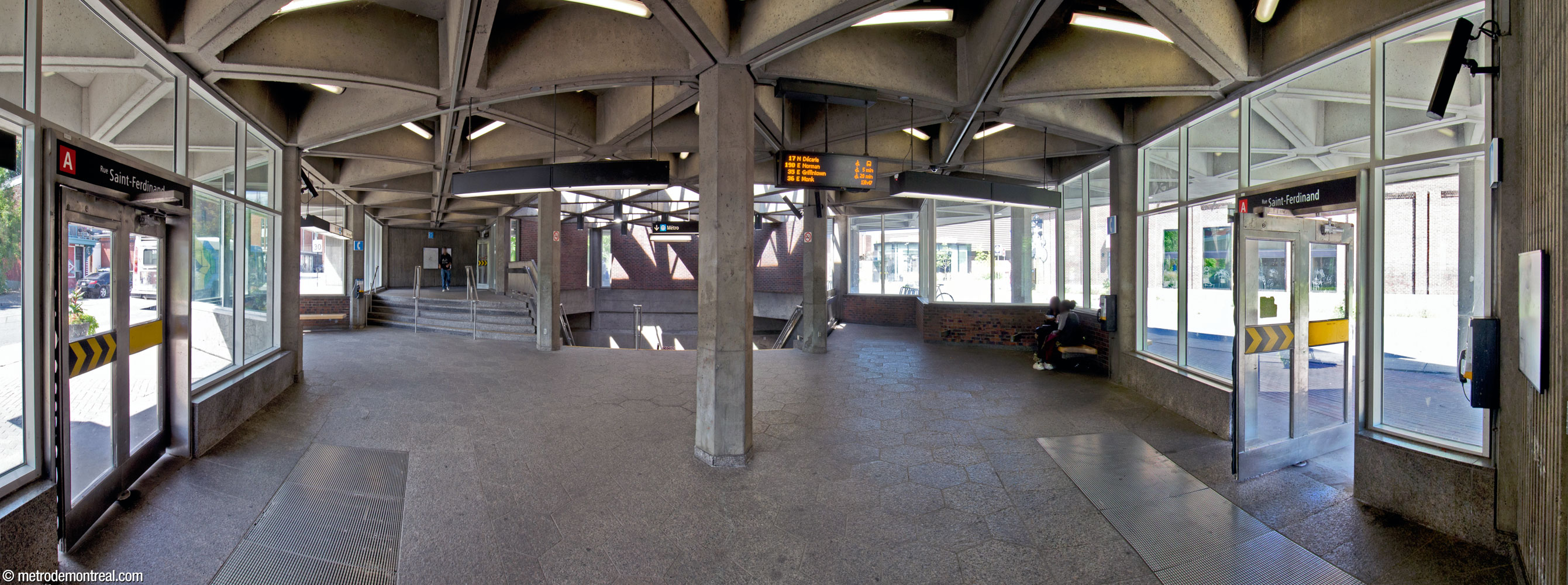 Interior of the Saint-Ferdinand headhouse. At left, a raised area leads to the north entrance. A hexagon-shaped skylight over the stairwell to the concourse admits sunlight to the light shafts below. The shape of the skylight and stairwell also repeat the theme of hexagons and equilateral triangles, as do the pillars and ceiling coffers.