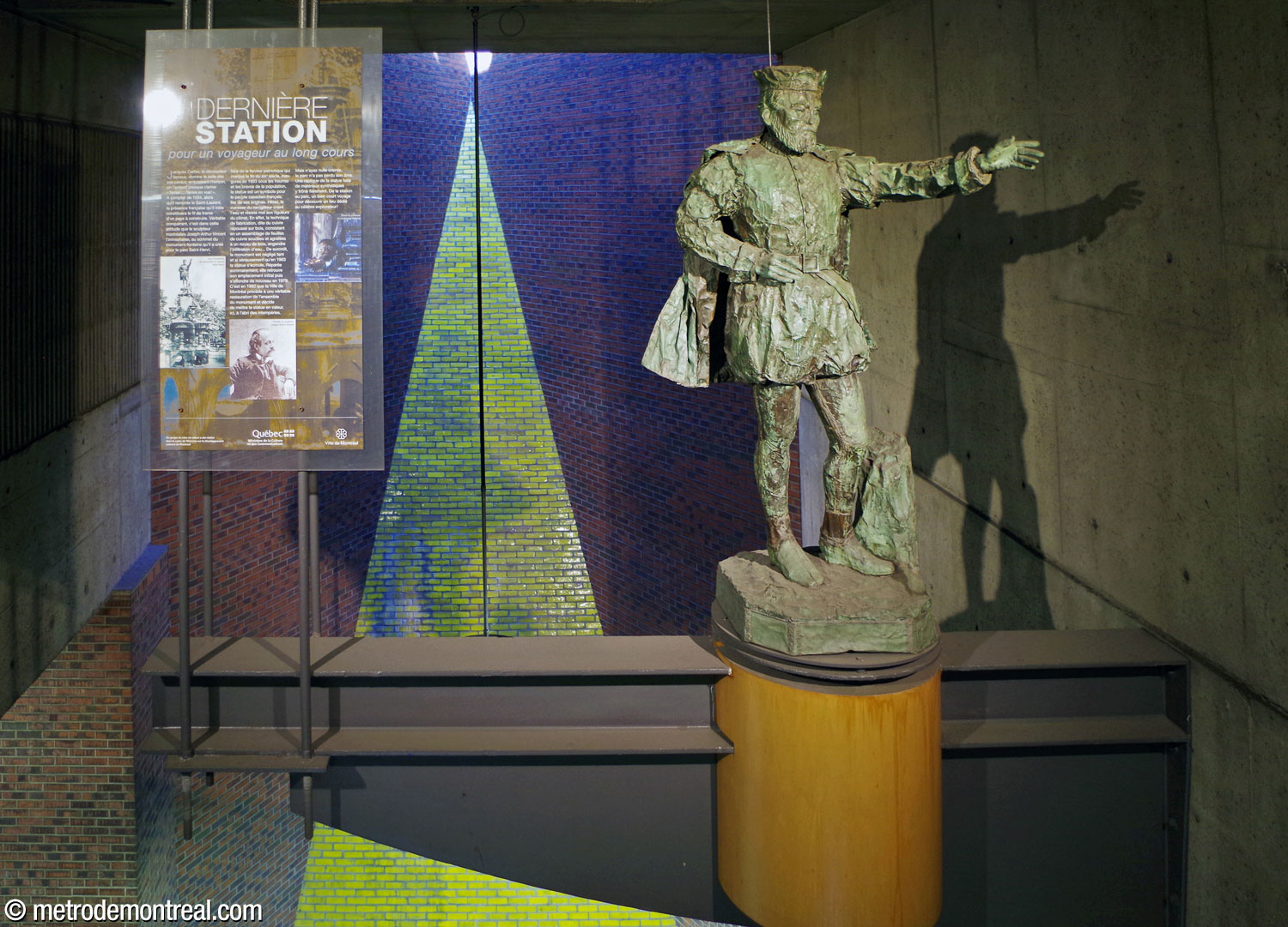 The statue of Jacques Cartier by Joseph-Arthur Vincent, on a pedestal facing the concourse and suspended in the light shaft above the Côte-Vertu platform, with an explanatory panel.