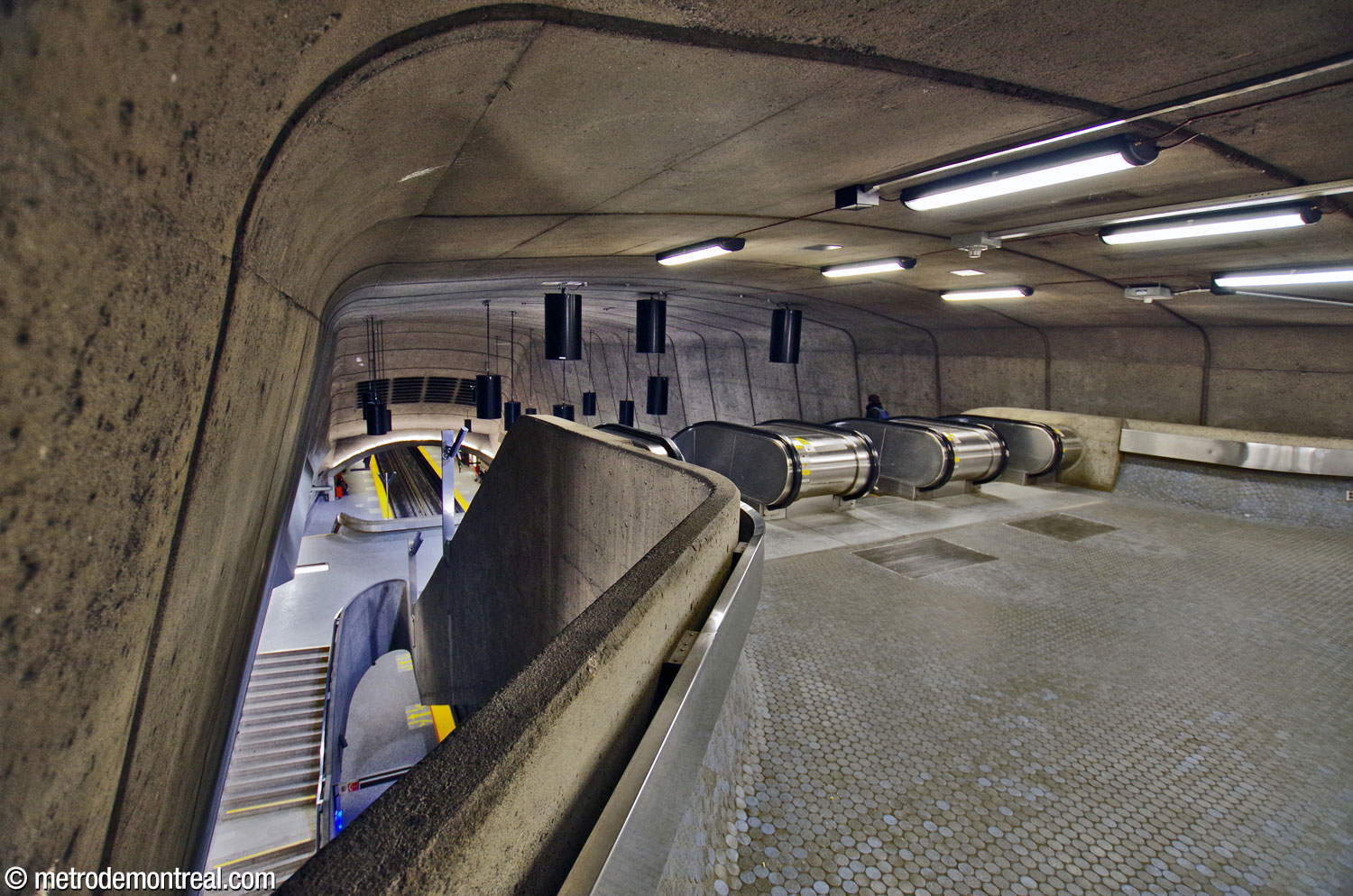 La tête de la volée centrale d’escaliers mécaniques, vue depuis la billetterie. En circulant vers les escaliers, les passagers découvrent progressivement le grand volume en contrebas.