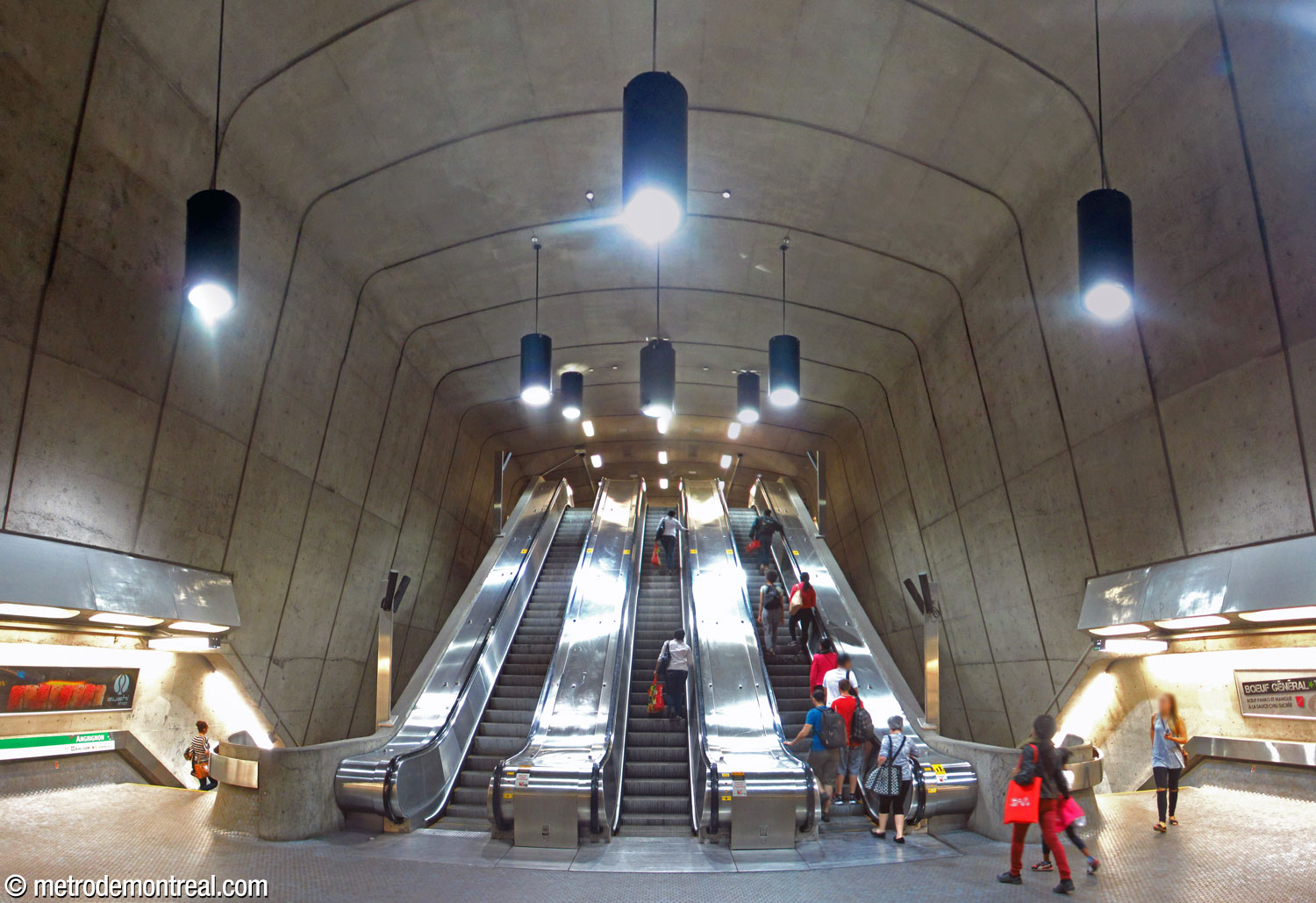 Vue en contre-plongée de l’axe unique de circulation verticale, une volée de trois escaliers mécaniques, qui traverse le grand volume entre la passerelle et la salle de contrôle.