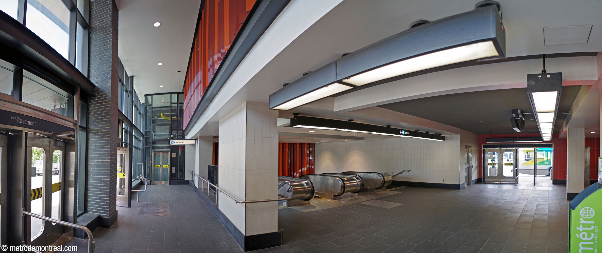 L'intérieur de l'édicule. À gauche, au-dessus de la sortie principale vers le boulevard Rosemont, l'élargissement de deux étages accueillant l'ascenseur vers le niveau de la billetterie. La large cage d'escalier vers la billetterie est au centre. À gauche, la sortie vers la boucle d'autobus. Des persiennes rouge et orange dissimulent des bouches d'aération naturelle à l'étage de l'élargissement et au-dessus des escaliers.