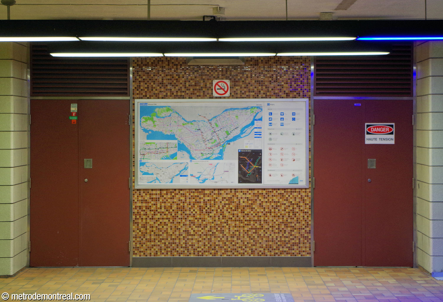 Un mur sous la passerelle, de facture plus récente, présente un carrelage aléatoire de tons de jaune, orange et brun, en harmonie avec la mosaïque d’origine. Les portes des locaux techniques sont peintes de rouge brique.