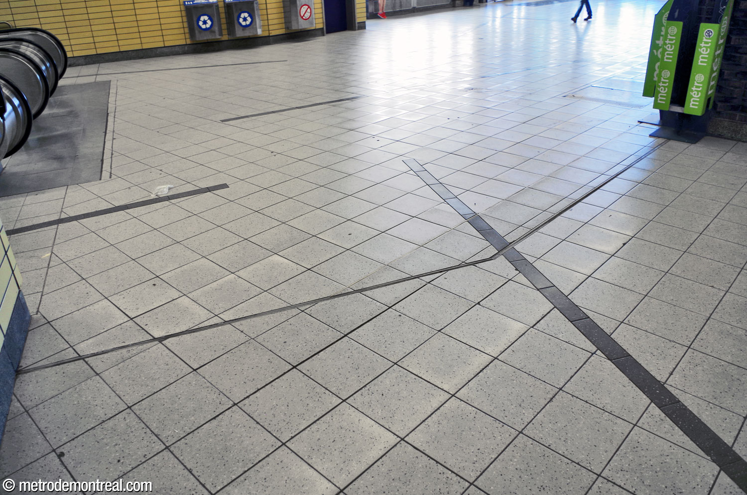 The tiled floor of the Berri Ouest entrance. The oblique lines of dark grey tiles interrupting the paler square tiling are found throughout the upper levels of the station.