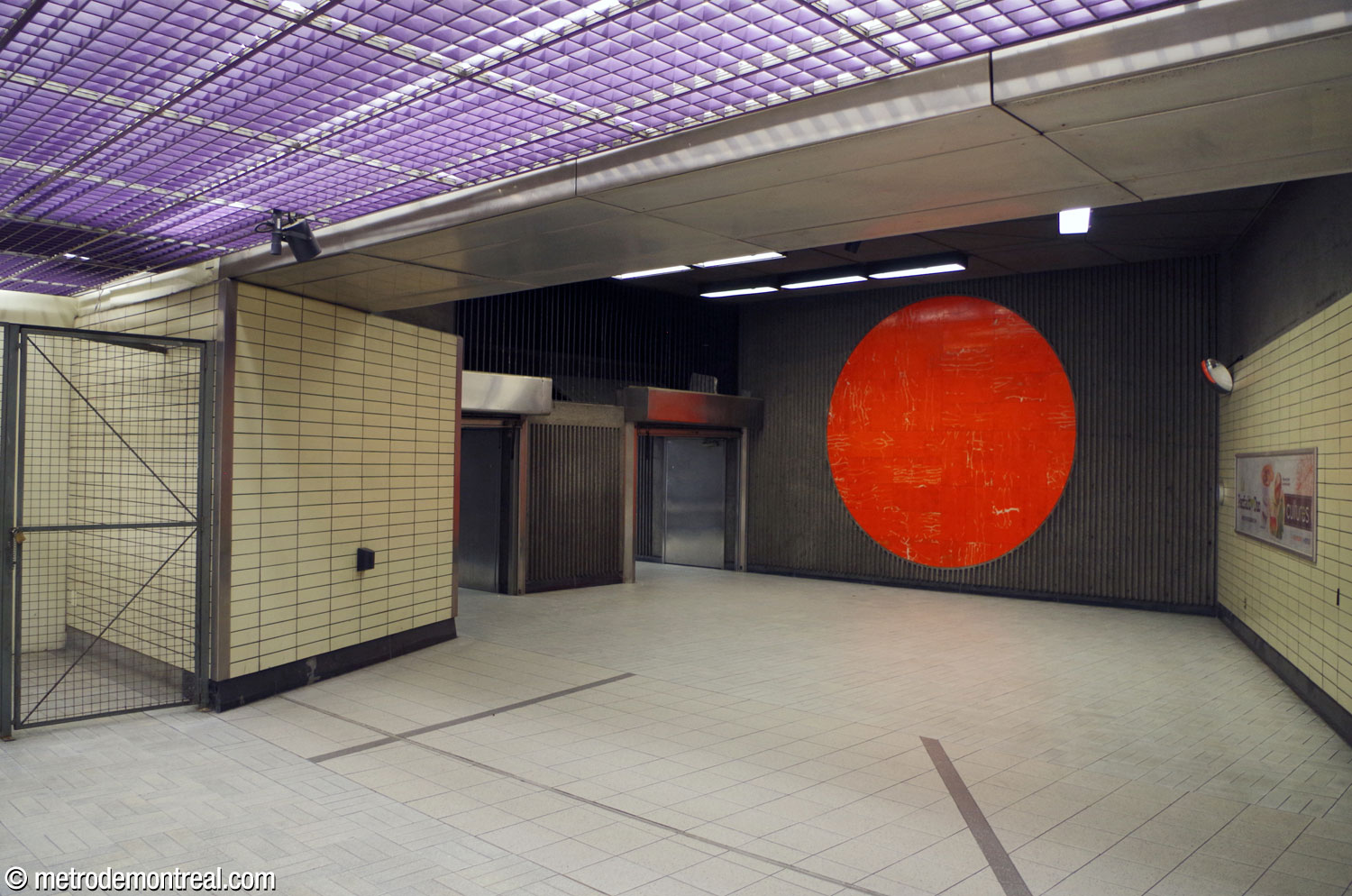 The foot of the stairs from the ticket hall level up to the Berri Est access. Mario Merola's large, circular mural Horizons, made of orange porphyry, occupies the adjacent wall.