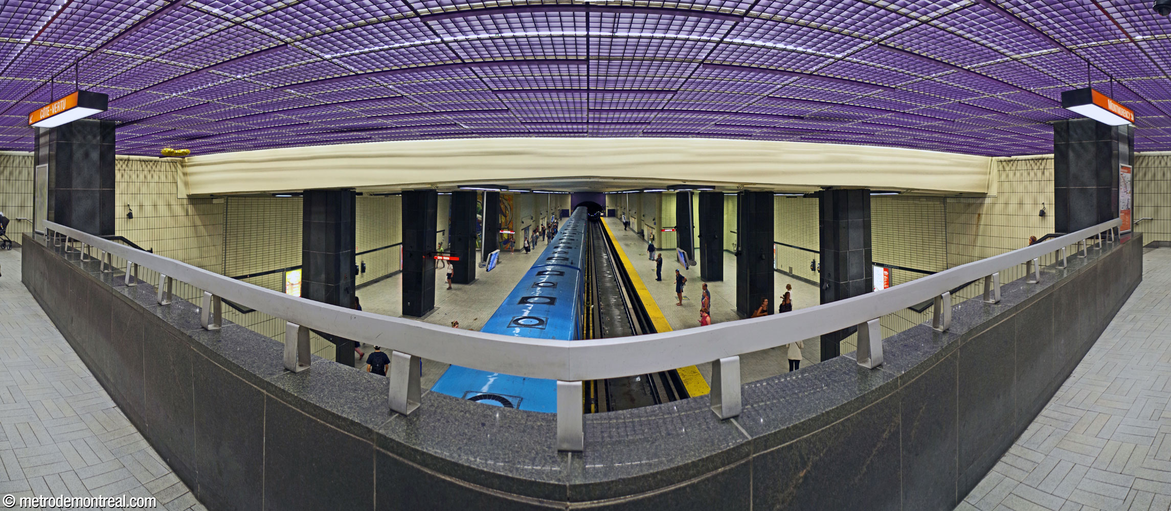 The overlook from the mezzanine fare-paid zone onto the platforms, facing north. The broad staircases to the platforms and the side aisles they lead to are on either side.