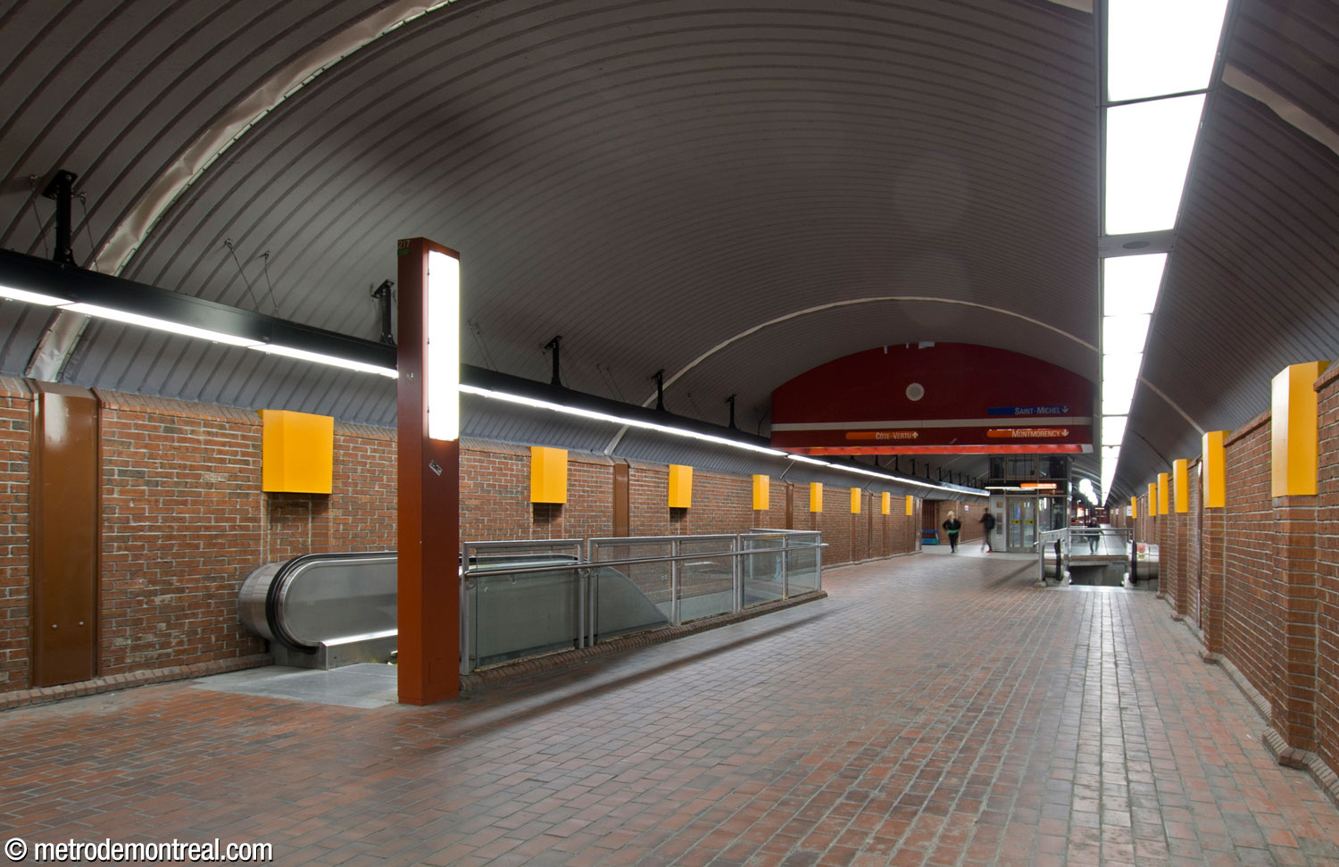 On arriving on the upper level of the central vault from the entrance, passengers first encounter two escalators against the walls, providing prompt passage to and from the lower level. An elevator connecting the two levels stands slightly further on.