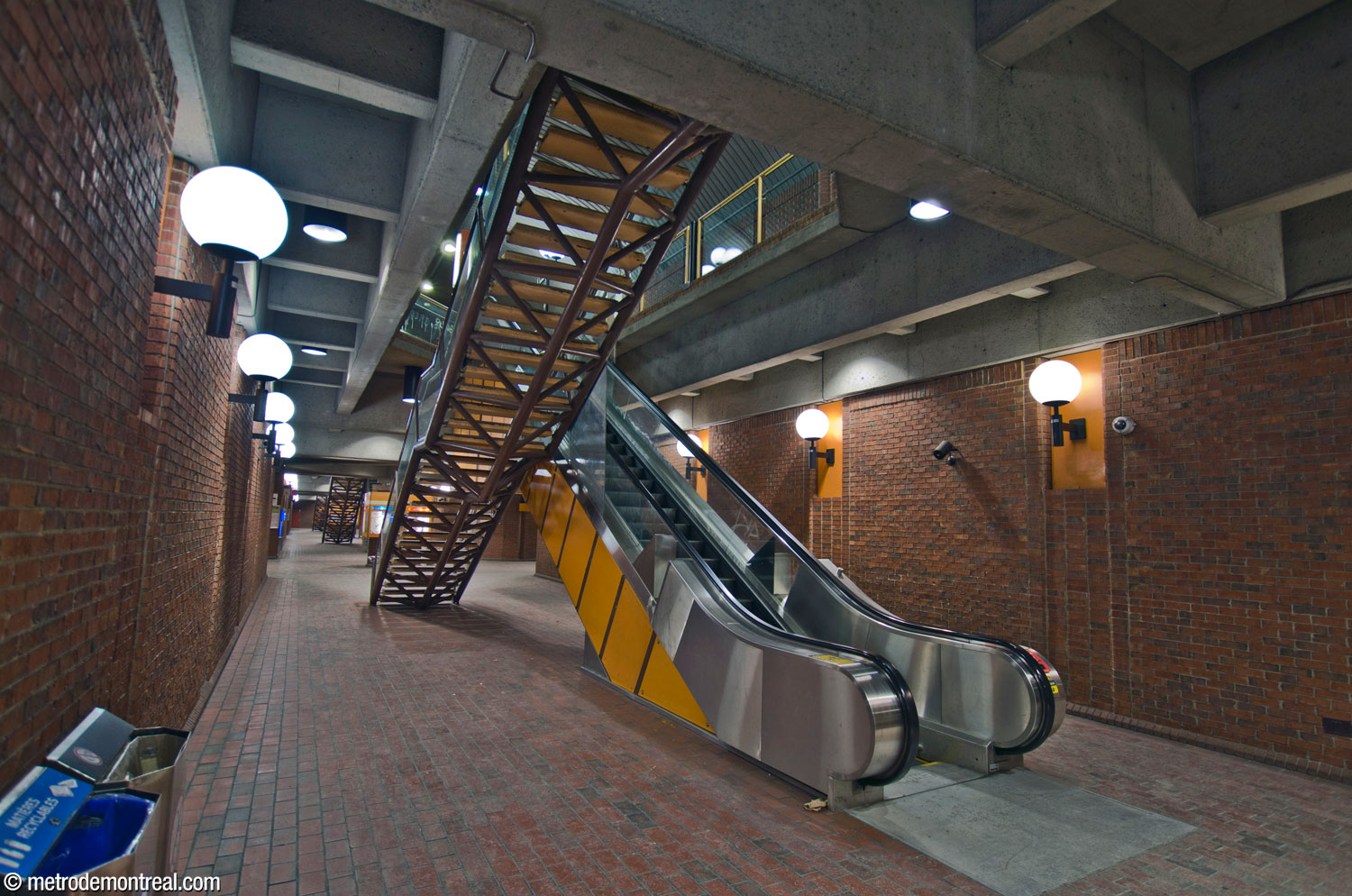 A paired escalator and fixed staircase between the levels of the central vault, seen from below. The escalator is a unique narrow model. The construction of the staircase, without risers and supported by a space frame, provides a feeling of lightness.
