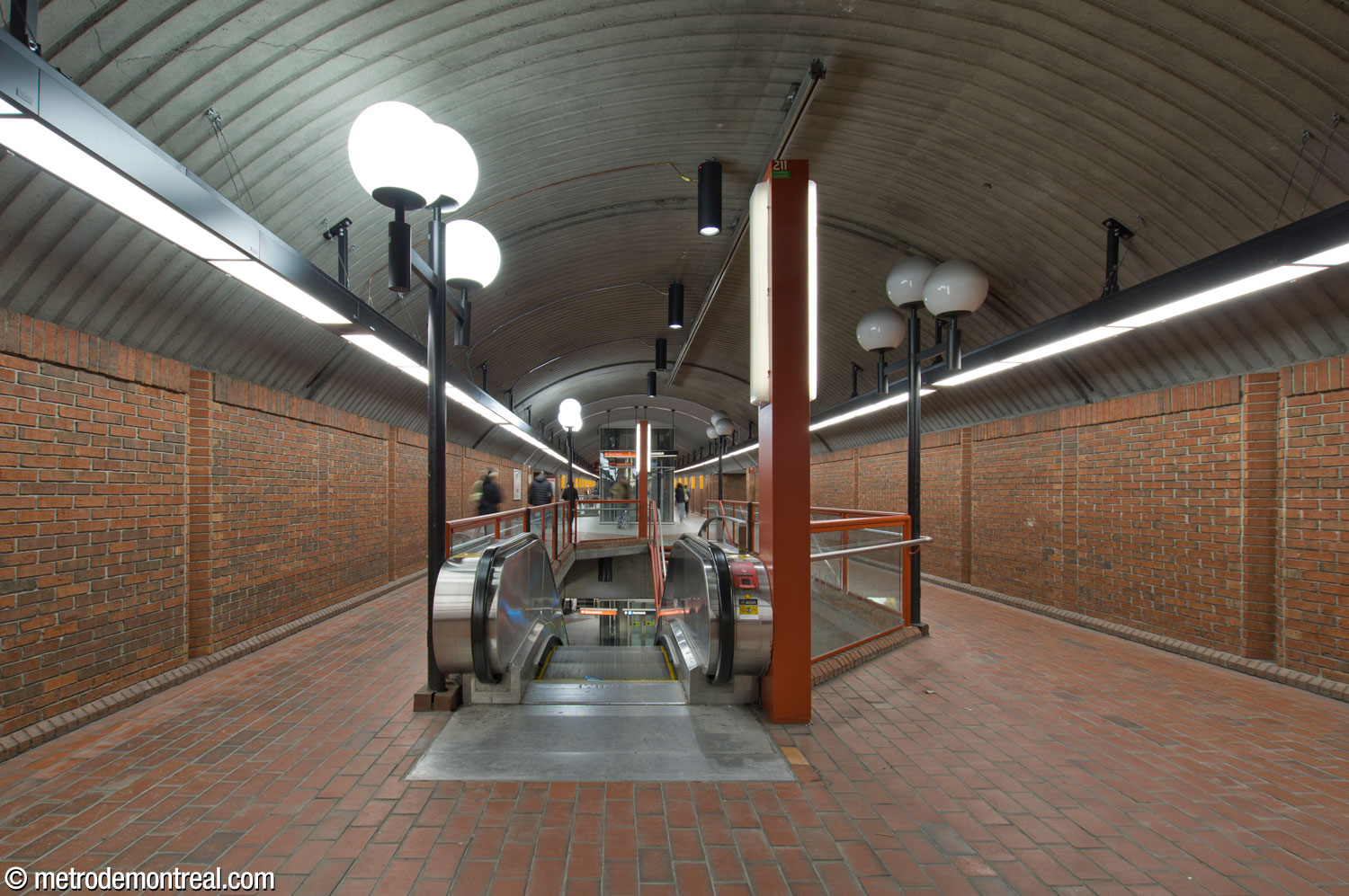 View of the central vault, upper level, facing westward, showing one of the stair and escalator wells. The elevator between the upper and lower platform levels is in the background.