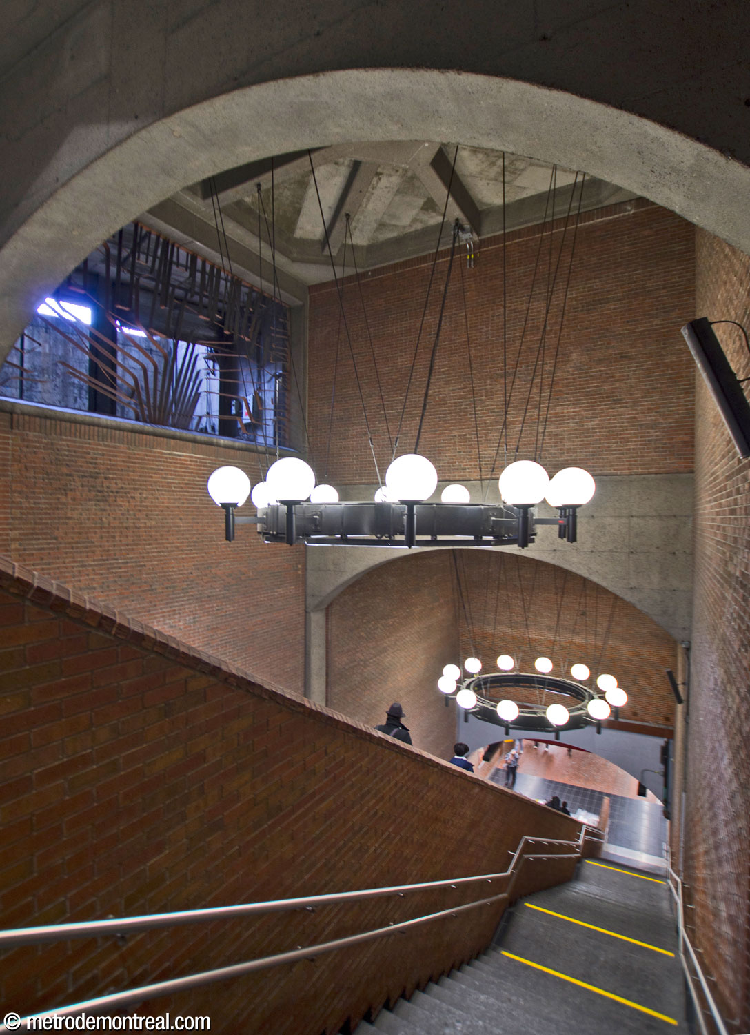 View of one of the successive volumes making up the main escalator well. Above the two chandeliers is a sculptural grille by Jean-Louis Beaulieu concealing a ventilation shaft.