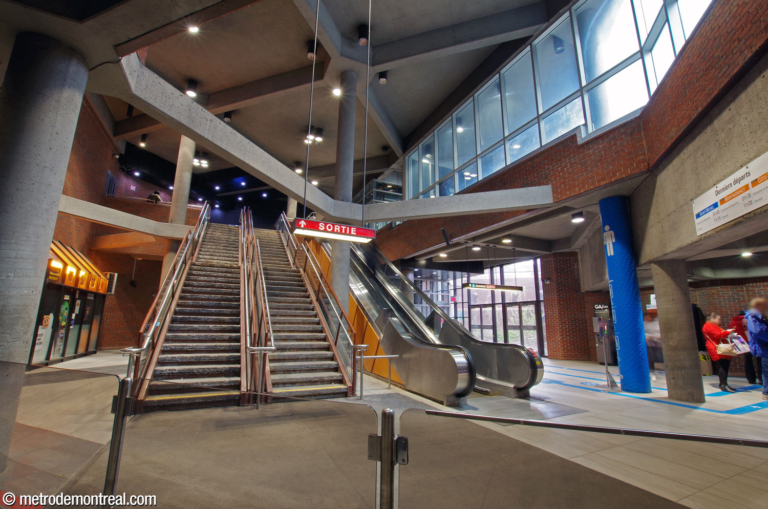 View facing the staircases and escalator leading to the exit. A concession is at left; at right is a large glass wall admitting light through the former sunken garden. The elevator up to the exit is located behind the escalator, next to the glass wall.