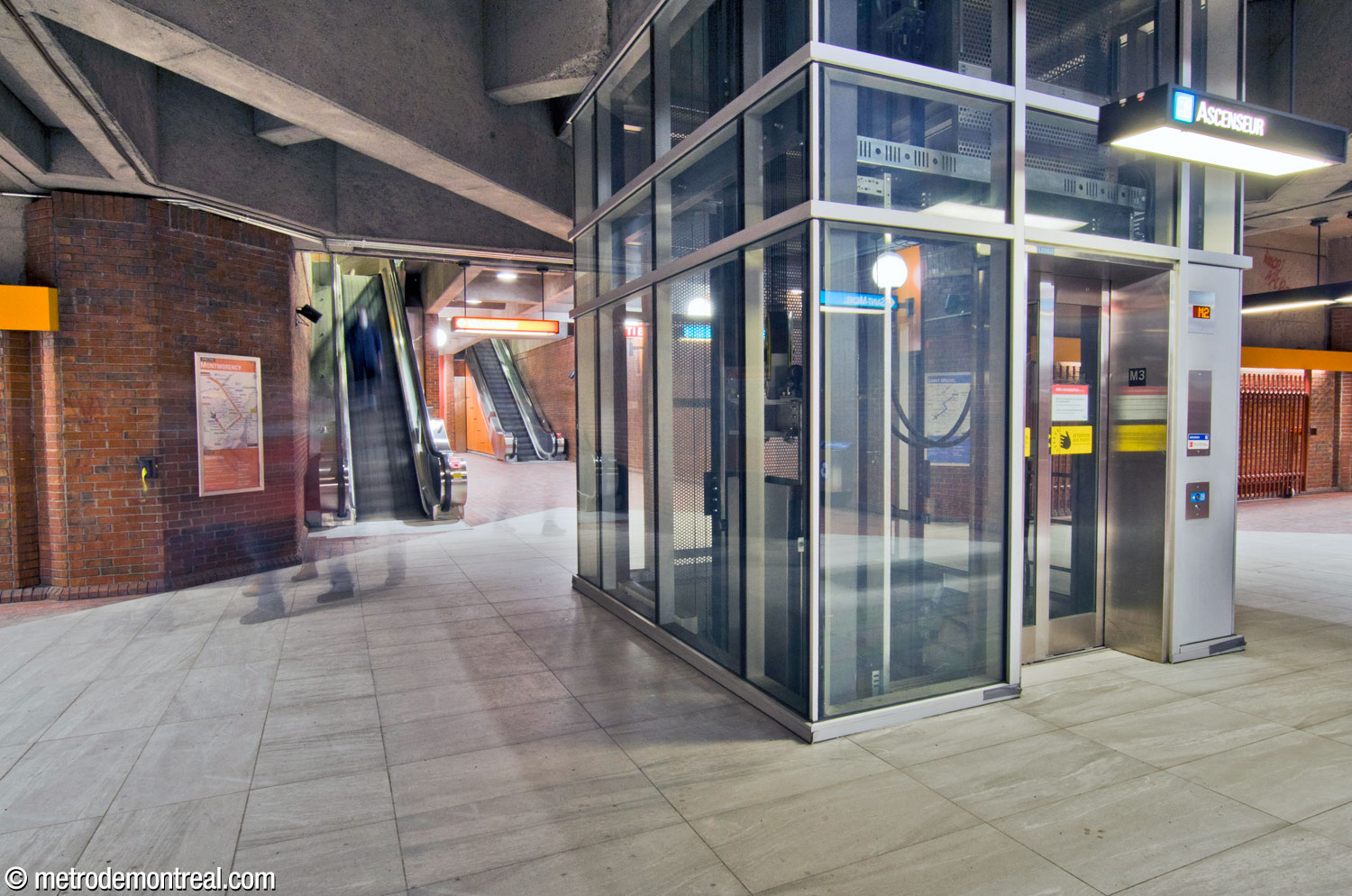 The upper and lower platform levels are connected by an elevator in the central vault at its intersection with the first transverse tunnel. In the background, escalators along the tunnel walls lead up to and down from the main escalators to the surface.