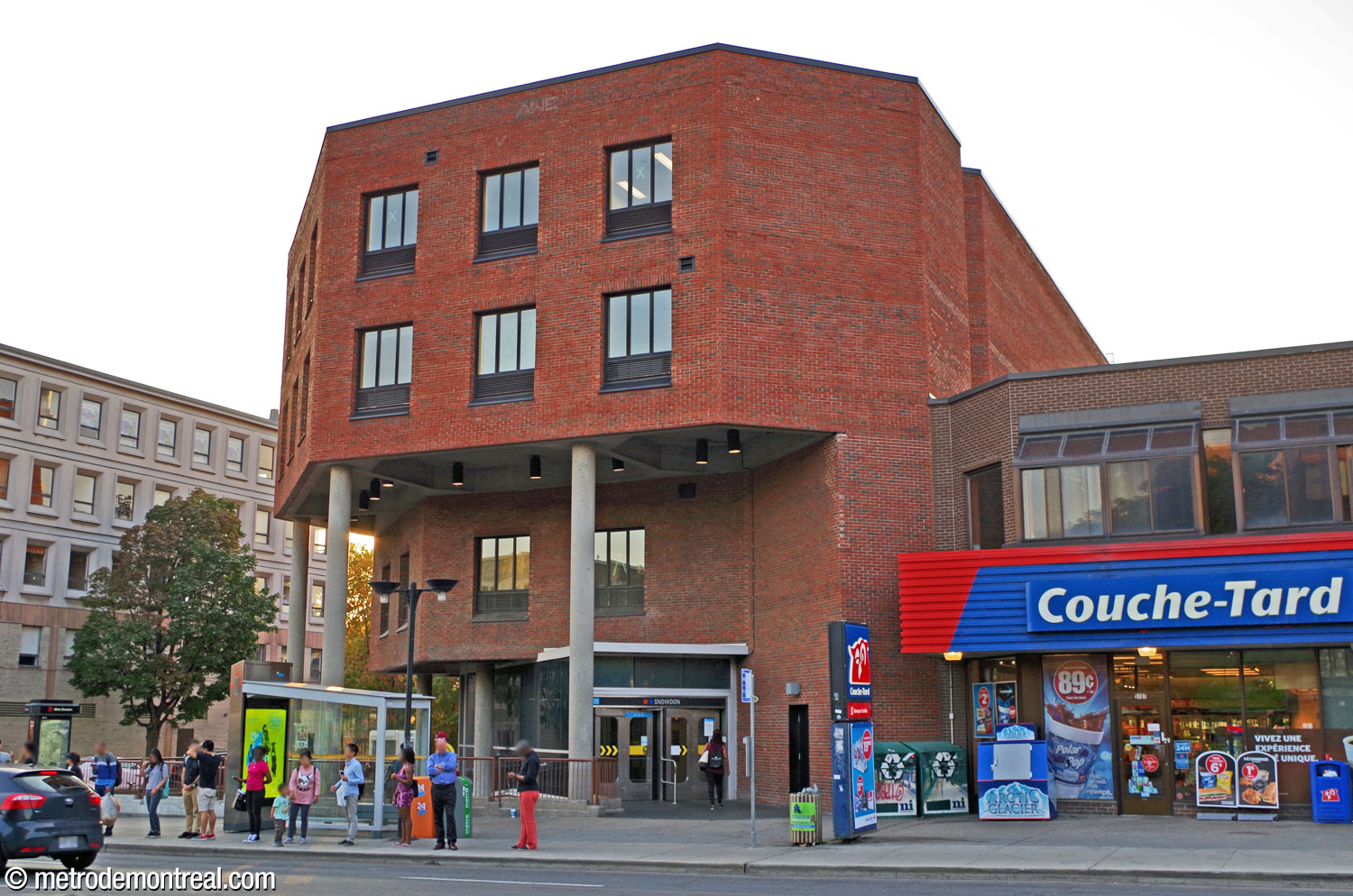 The station's headhouse, a four-storey brick building incorporating STM facilities in the upper levels. The overhanging section, supported on columns, shelters a sunken area alongside the entrance that formerly housed a garden.