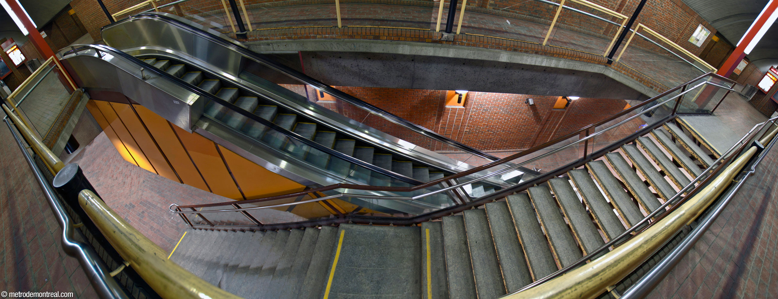 A paired escalator and fixed staircase in the central vault cross by each other, seen from above.