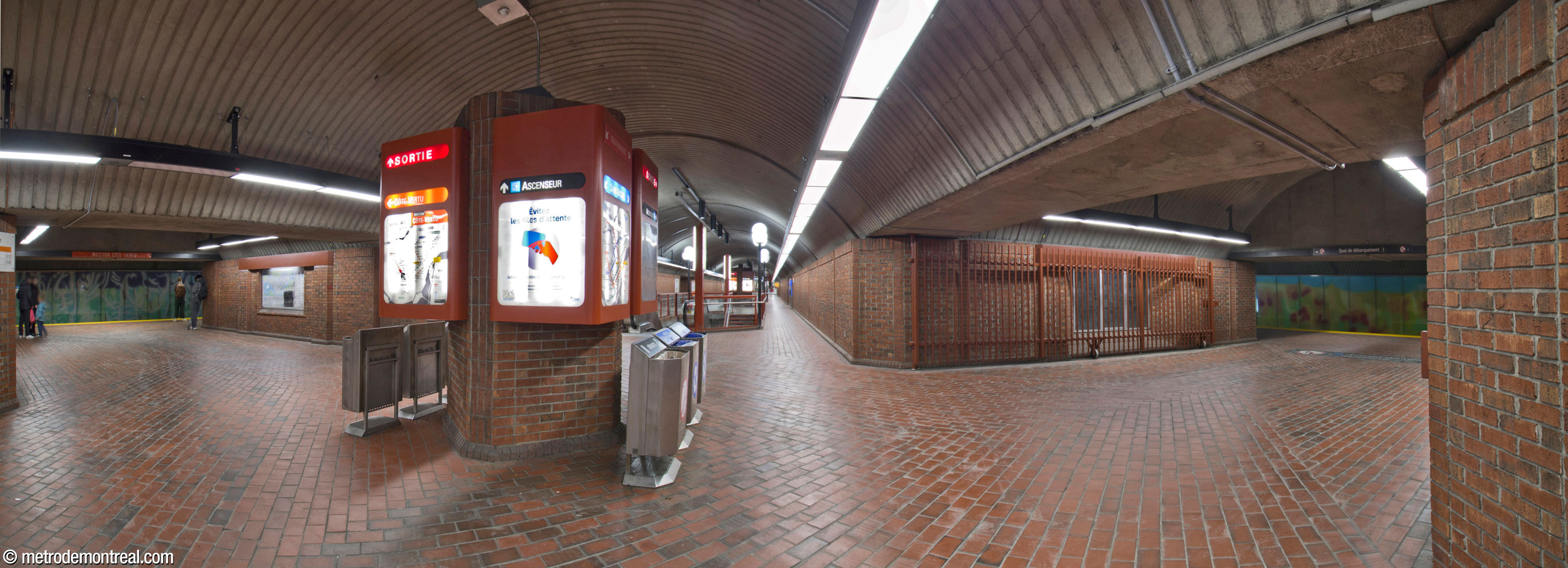 Panorama of the upper level of the central vault of Snowdon metro station, looking towards the exit. The connecting tunnels on either side connect the central vault to the parallel platform vaults: the orange line on the left, the blue line on the right.