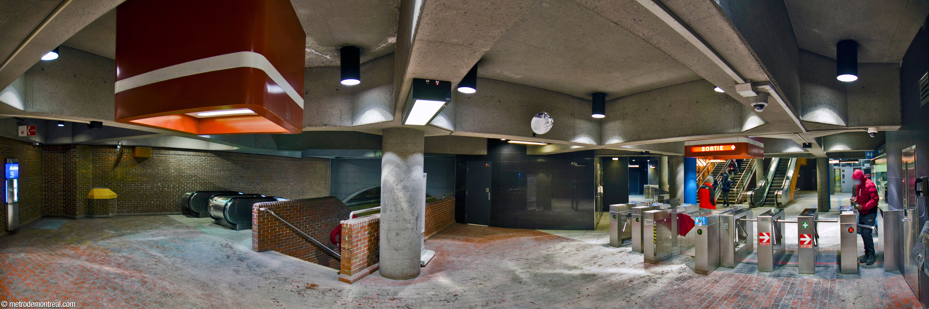 Panorama of the ticket hall. At left, the escalator well down to the platforms. At centre-right, the fare-paid zone wraps around to include a separate ticket gate in front of the elevator to the platforms.