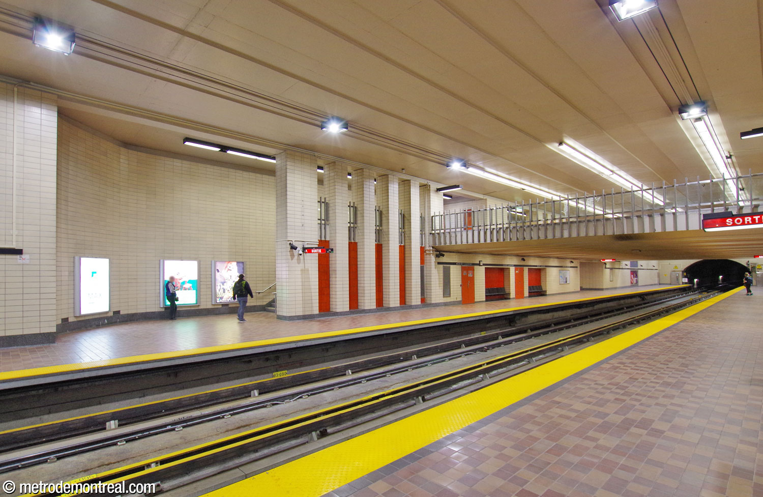 The portion of the Honoré-Beaugrand platform under the mezzanine. A series of square columns and red-orange tiled screens separate the eastern staircase from the platform. The station's only platform benches are located underneath the mezzanine.