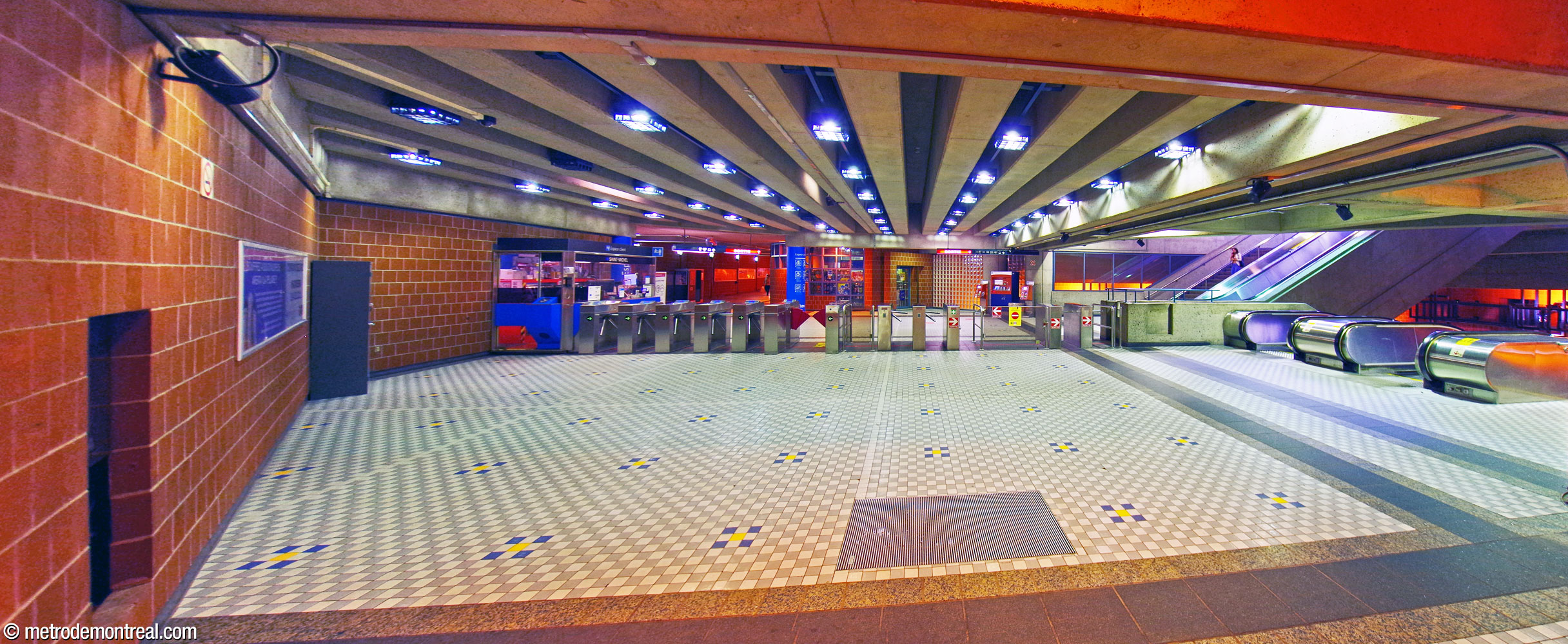 Panorama of the ticket hall, looking west from the fare-paid zone toward the gateline. The staircases up to the east headhouse and down to the platforms are at right. The hallway to the west headhouse is at centre-left beyond the turnstiles.
