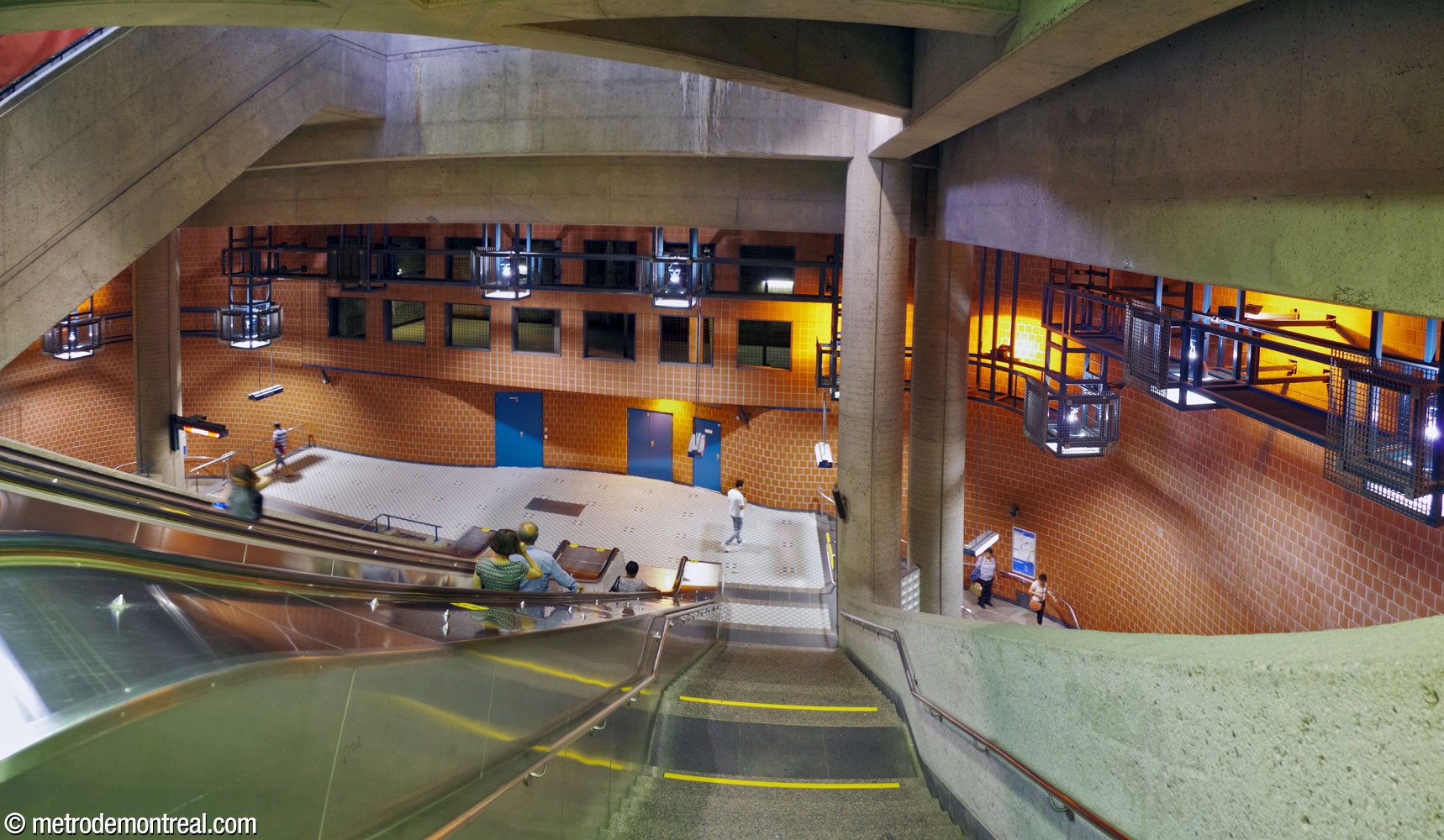 Looking down the main staircase to the transept-level landing above the departure platform. The station's distinctive lamps are visible along the perimeter of the main volume. Note the curved wall along the rear of the landing and the array of square ventilation openings above. At top left is the stairwell up to the eastern headhouse from the ticket hall.