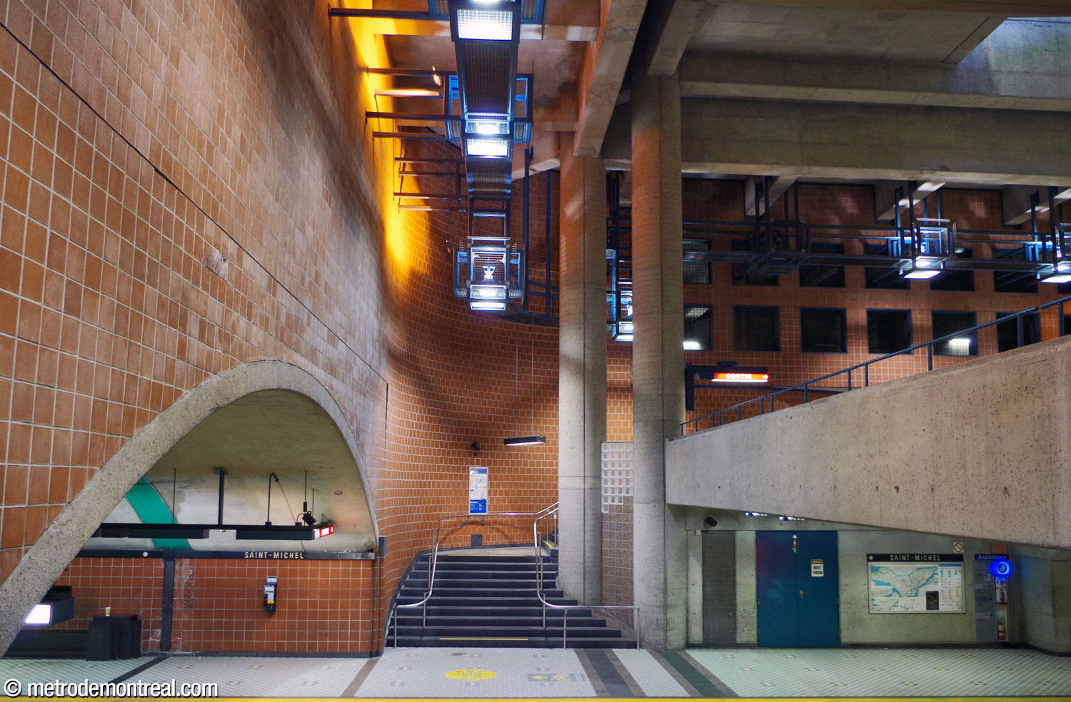 View of the central volume and the departure platform, viewed from the stairs up from the arrival platform. At centre is one of the four pairs of pillars supporting the roof of the volume and the east headhouse atop it. At right is the parapet of the crossover. Behind the distinctive light fixtures (top centre and right), a grid of square openings on the back wall provides ventilation.